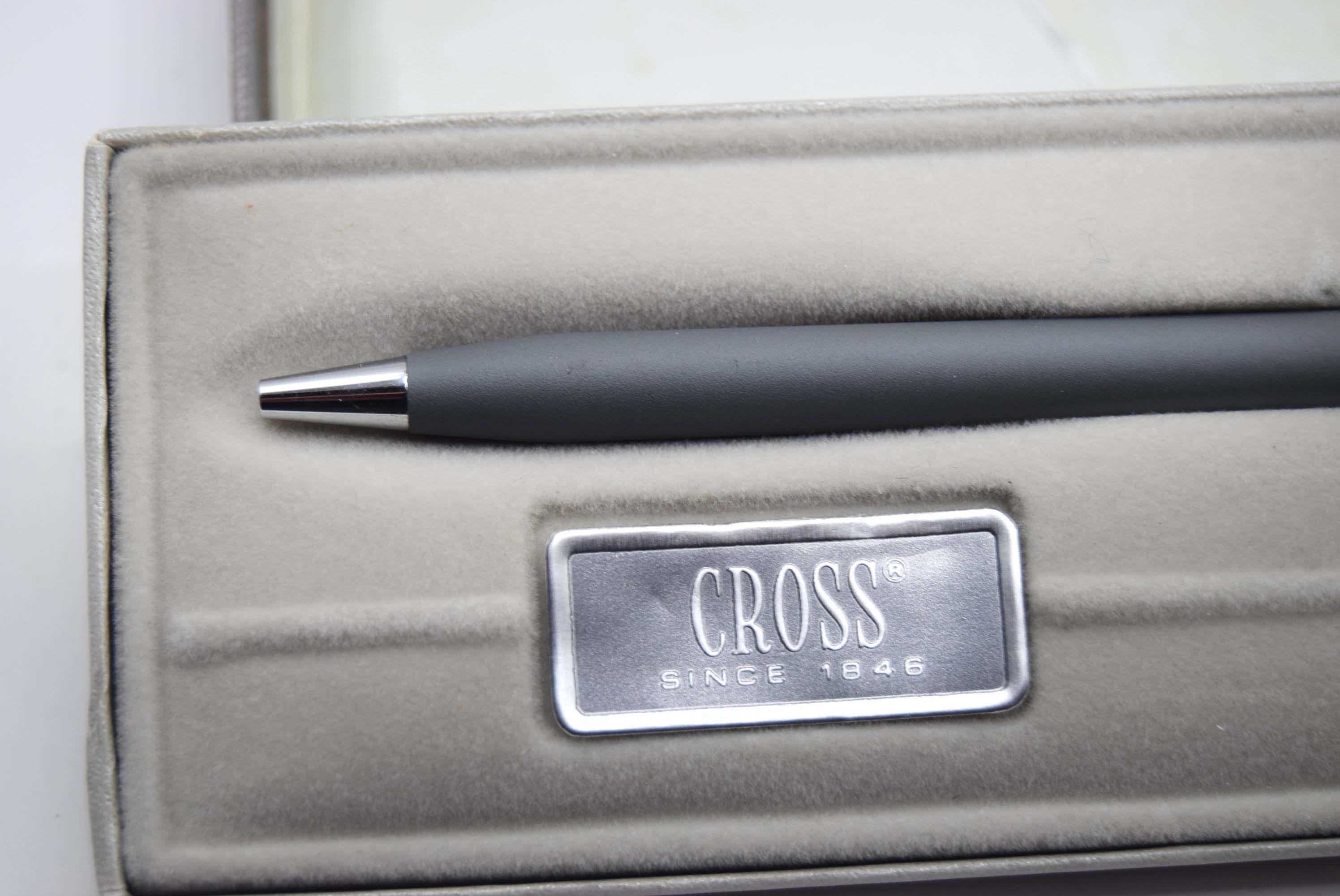 Gray pen case with a black pen and 'Cross' logo on a light gray background