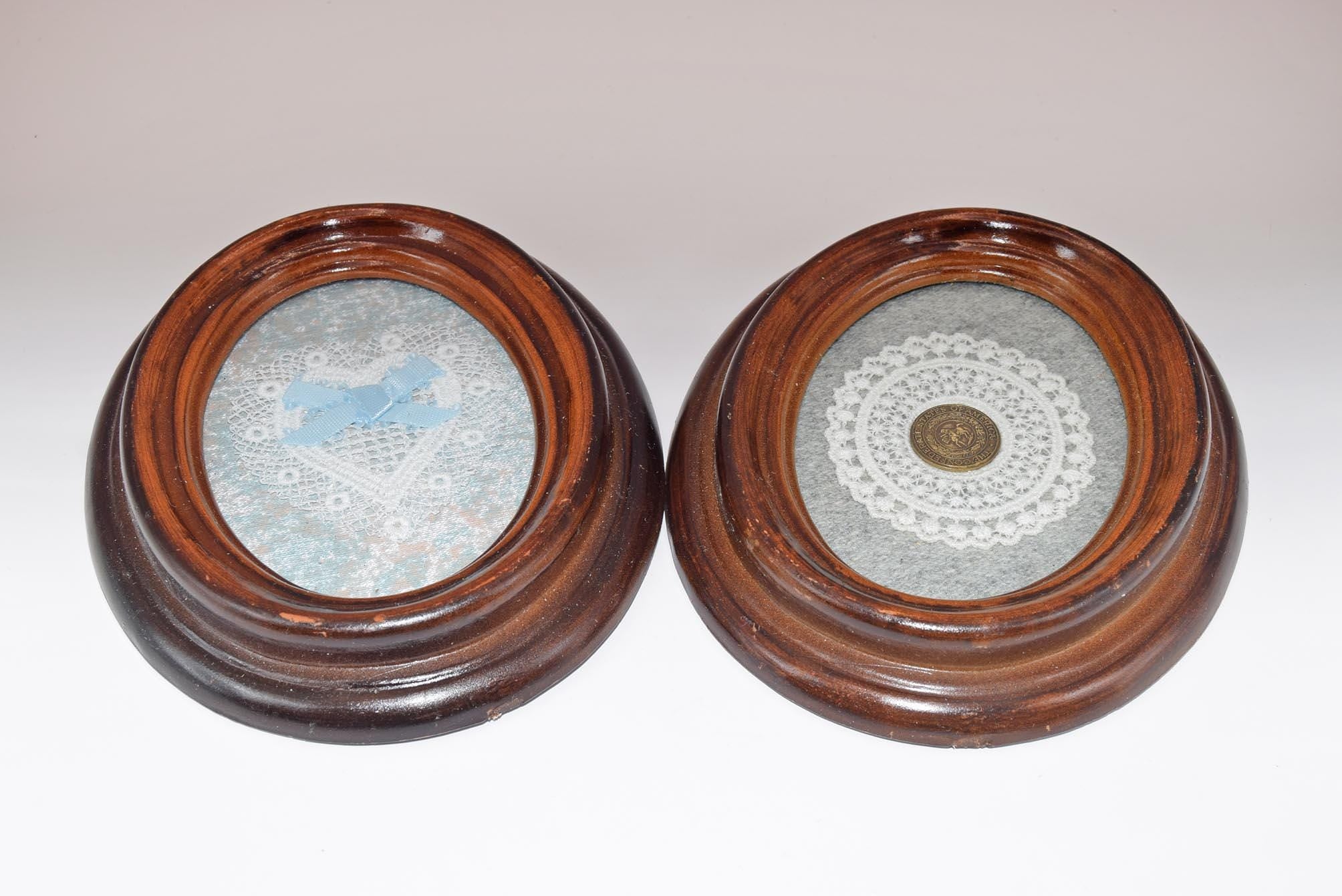 Two round wooden frames with decorative contents on a light gray background