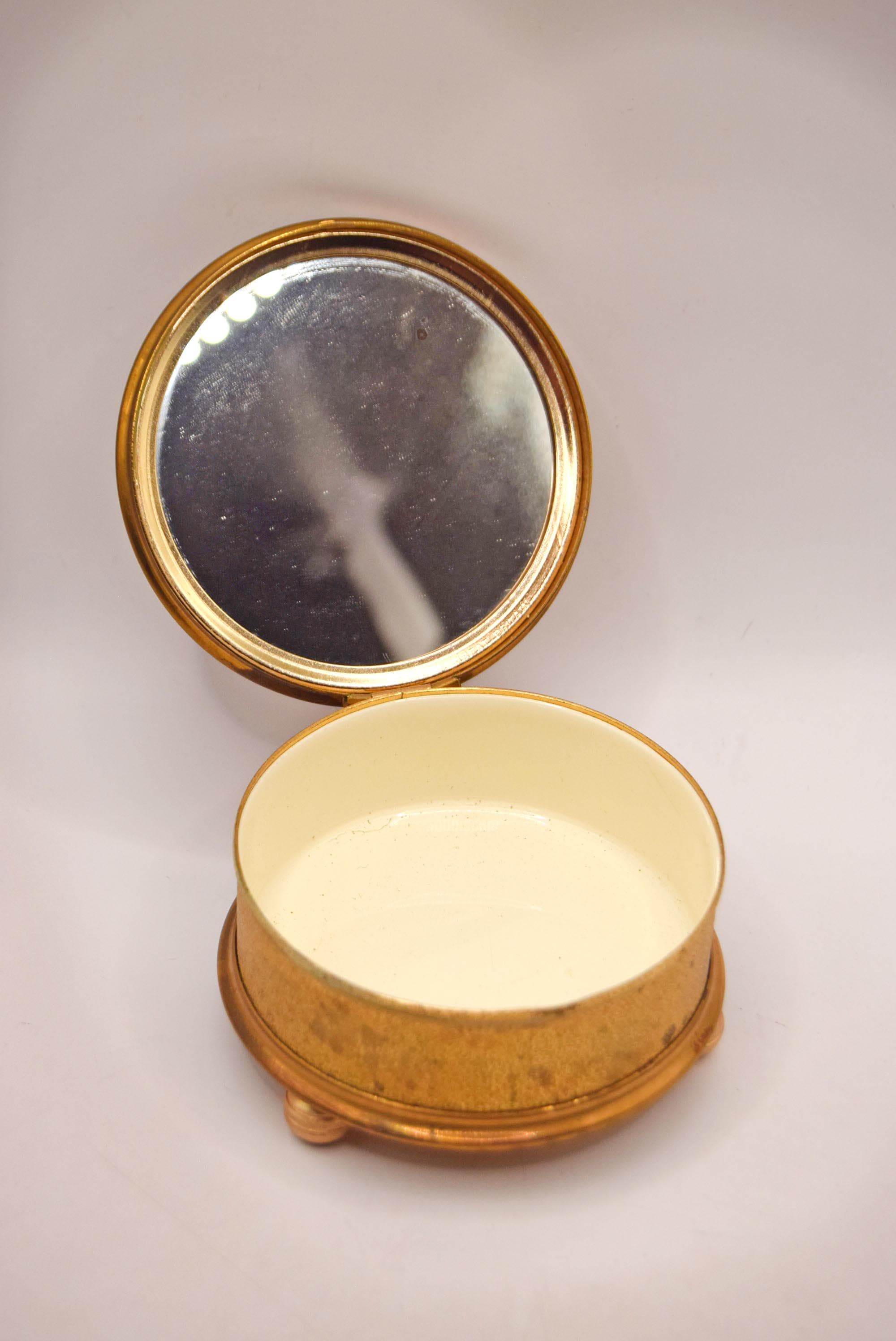 Gold compact mirror with a white interior on a light gray background