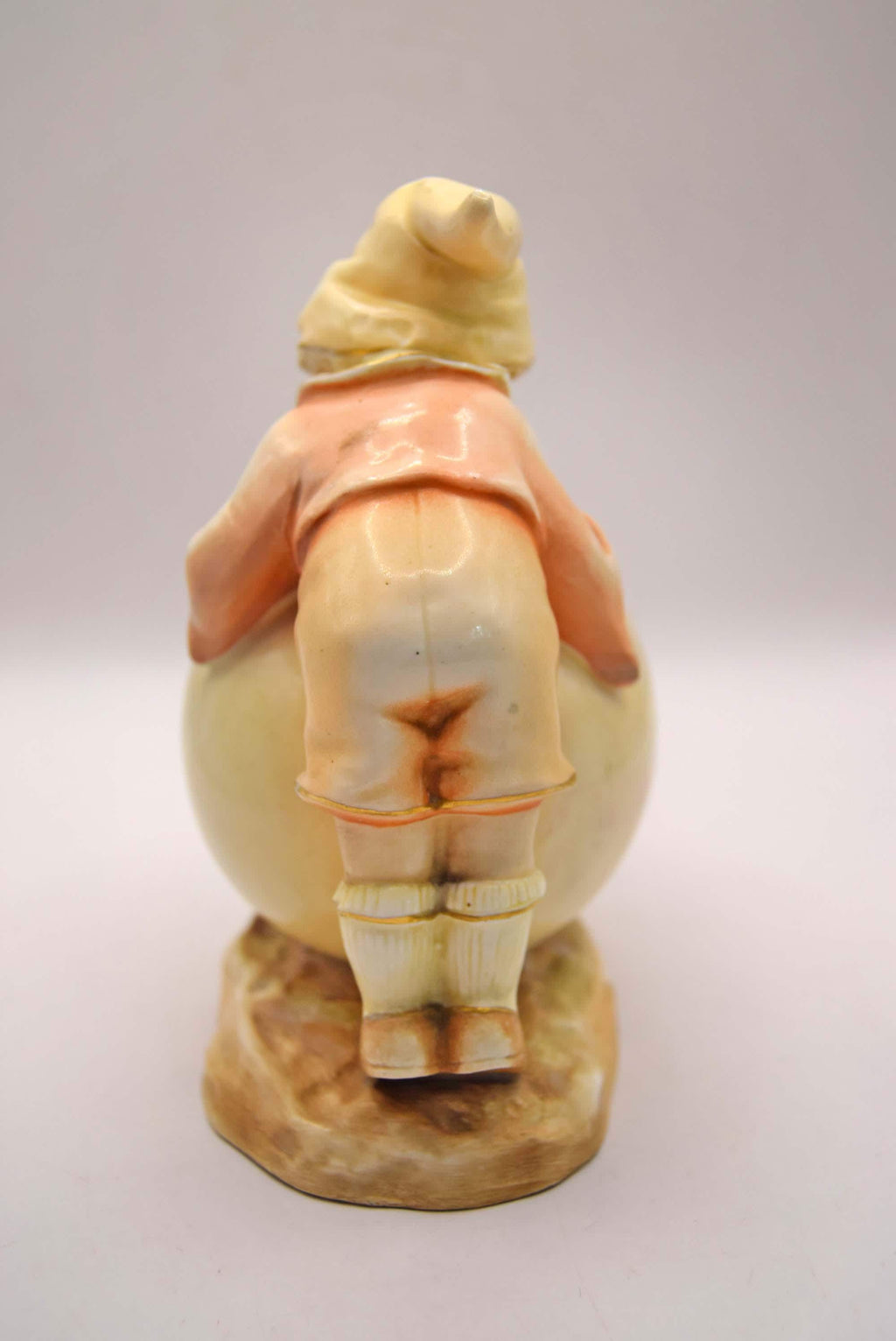 Vintage ceramic figure of a person in a coat and hat on a white background
