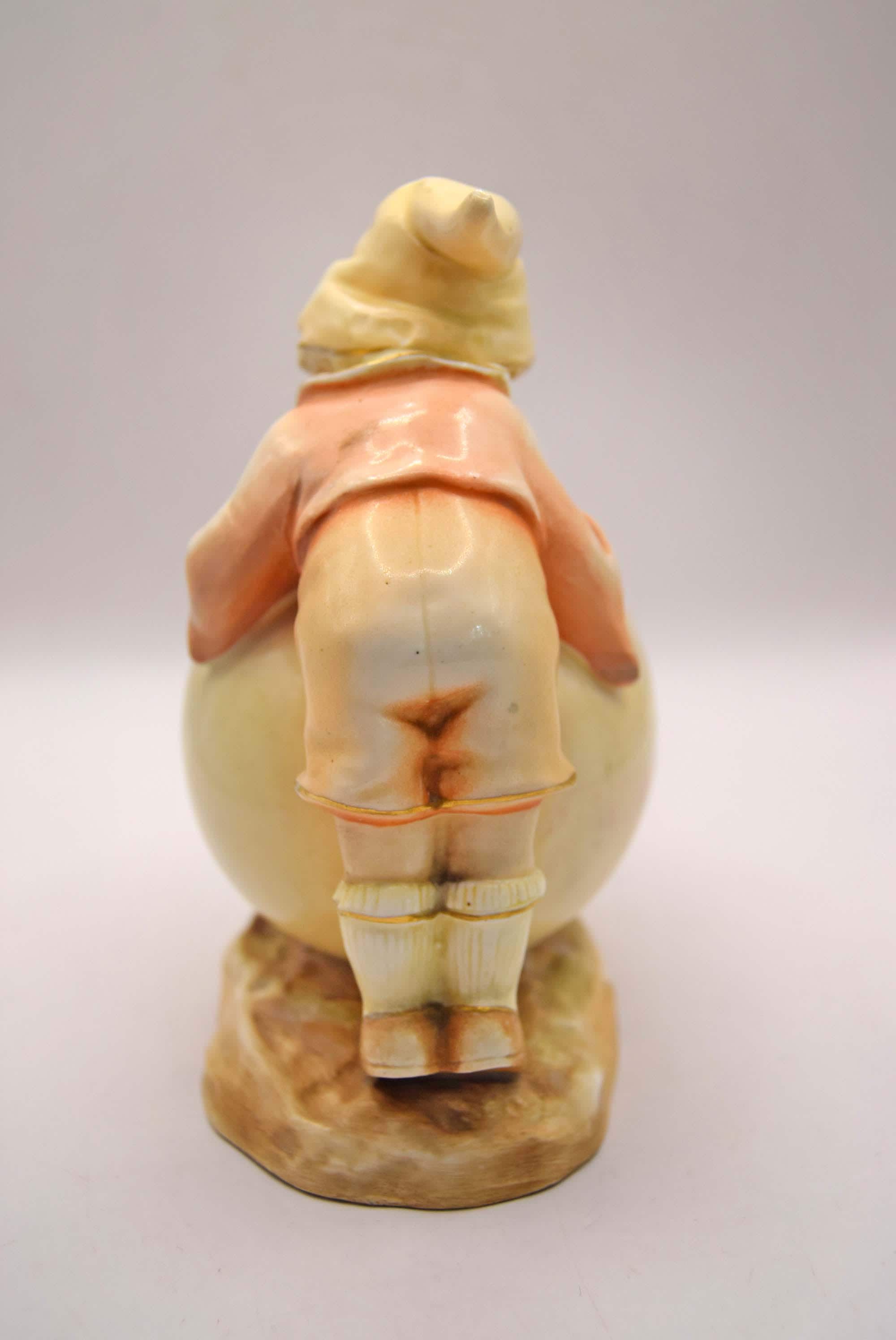 Vintage ceramic figure of a person in a coat and hat on a white background