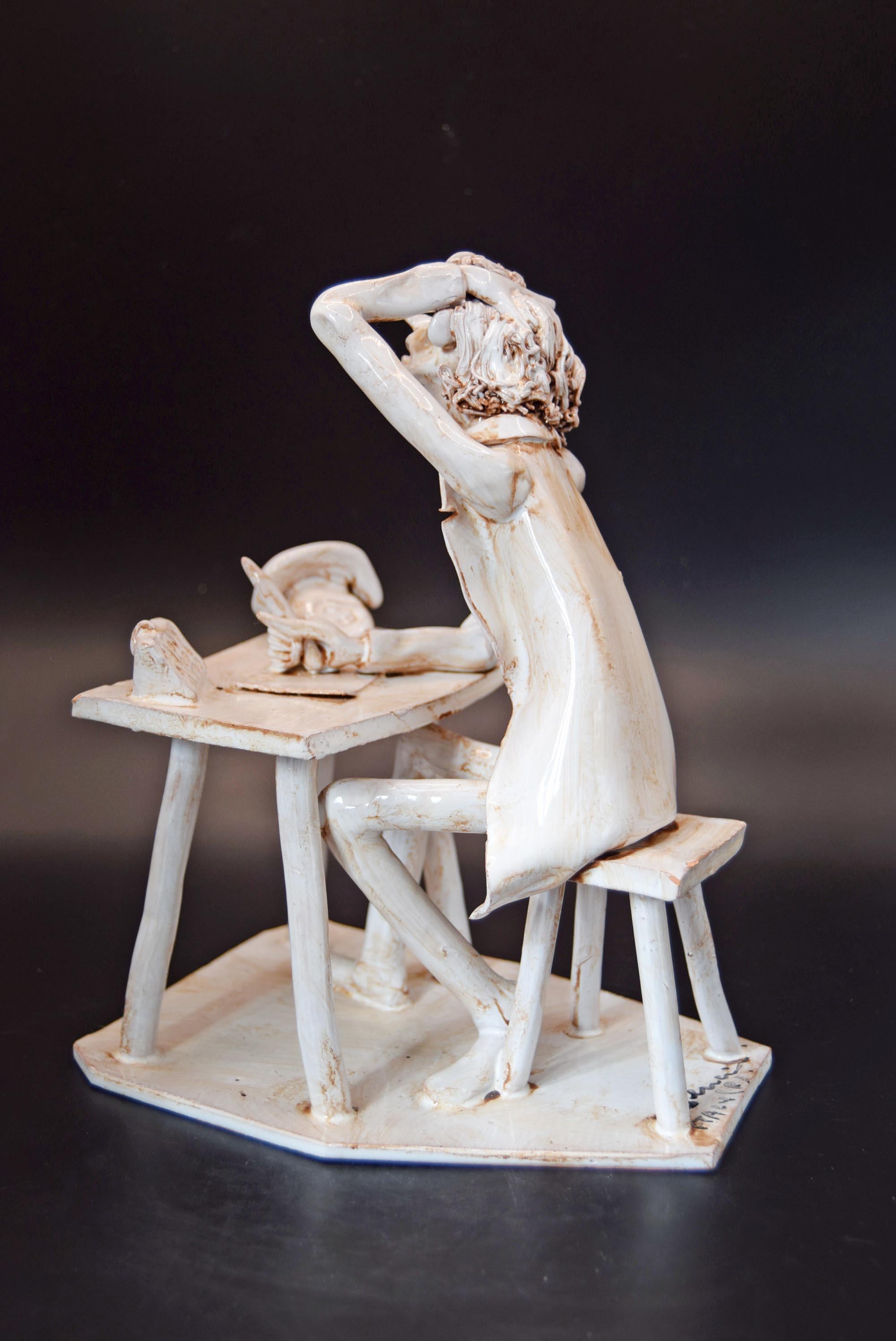 White ceramic sculpture of a person sitting at a desk with a cat on a dark background