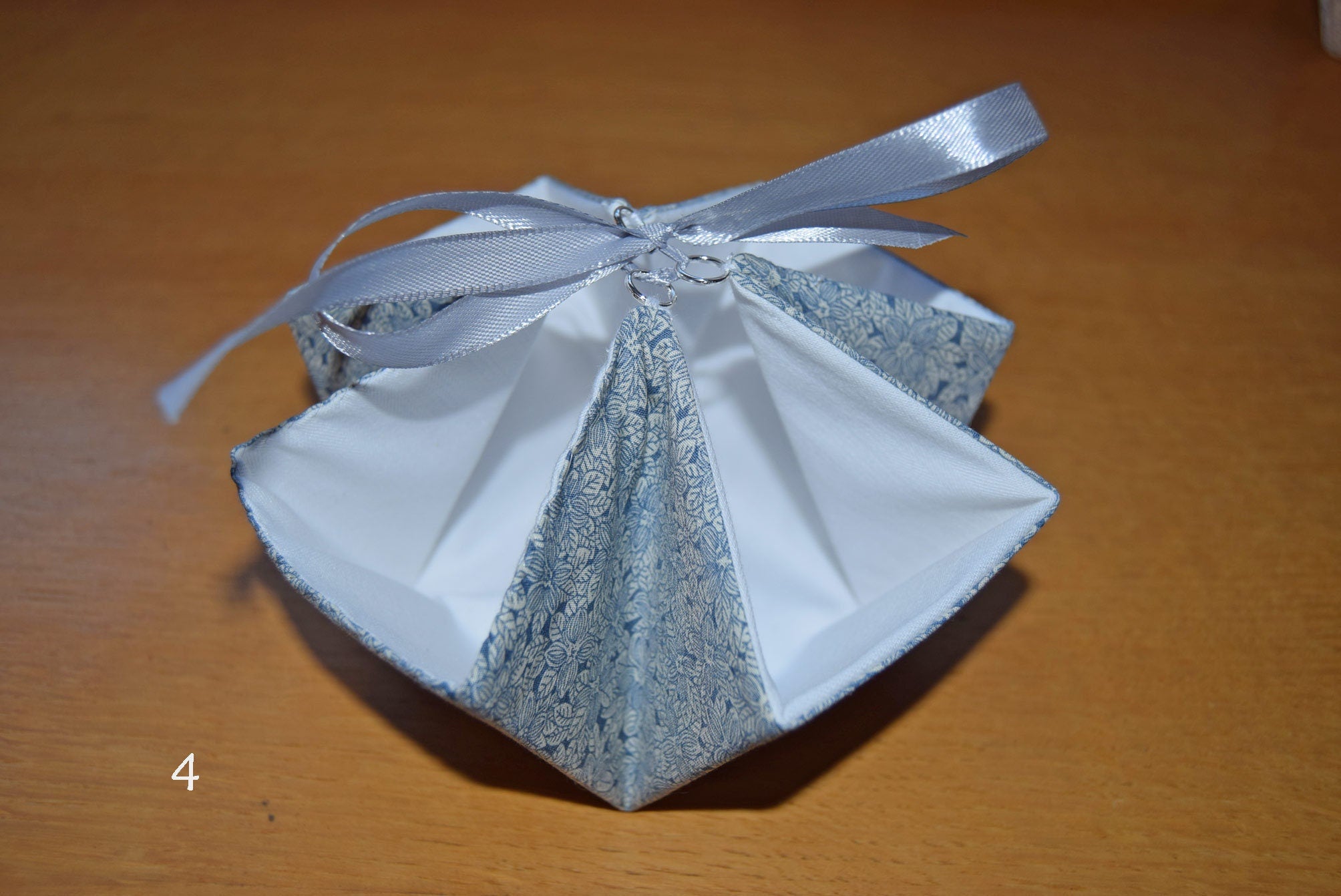 Decorative handmade gift basket with a white ribbon on a wooden surface