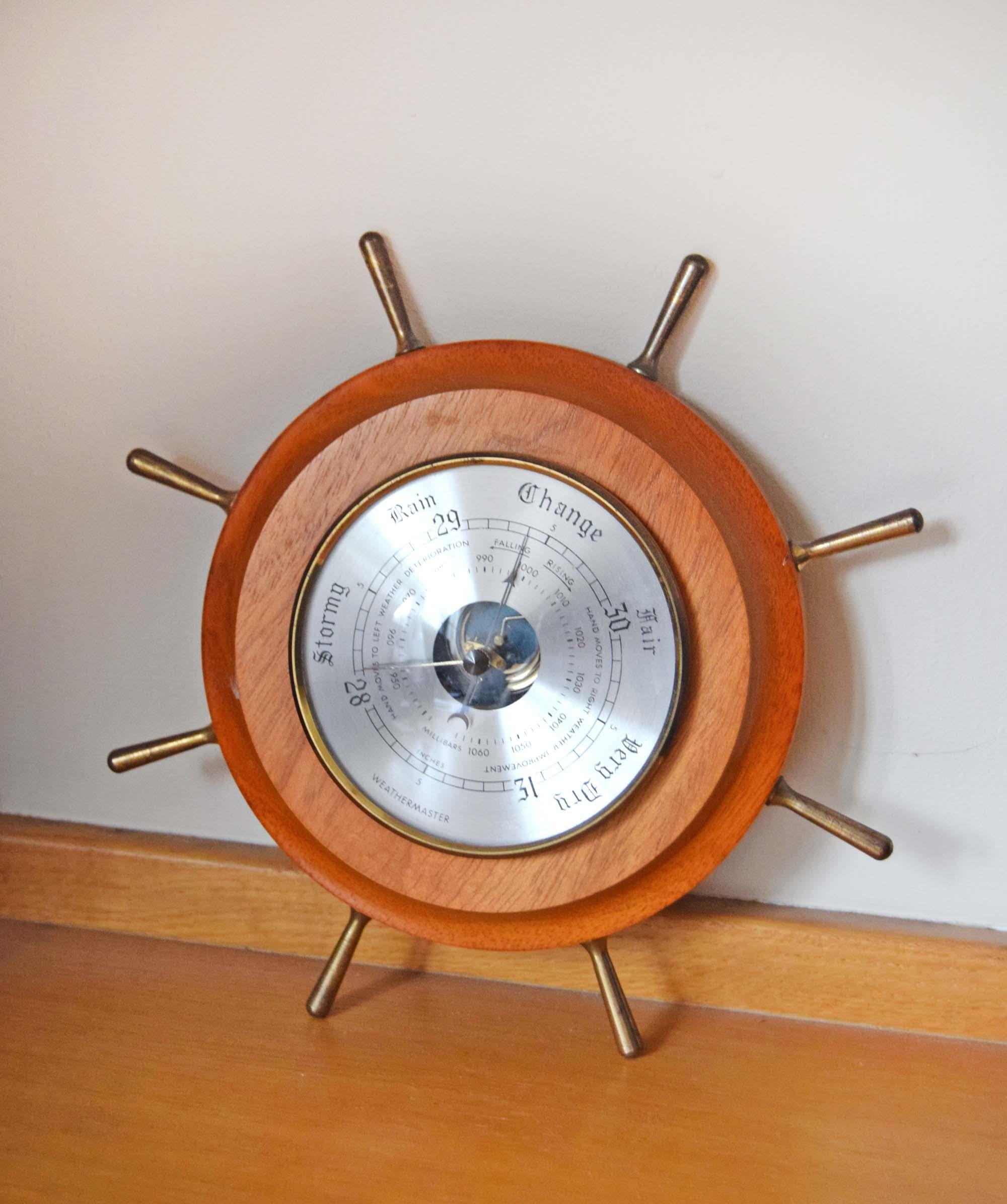 Wooden ship's wheel with a barometer on a wooden surface