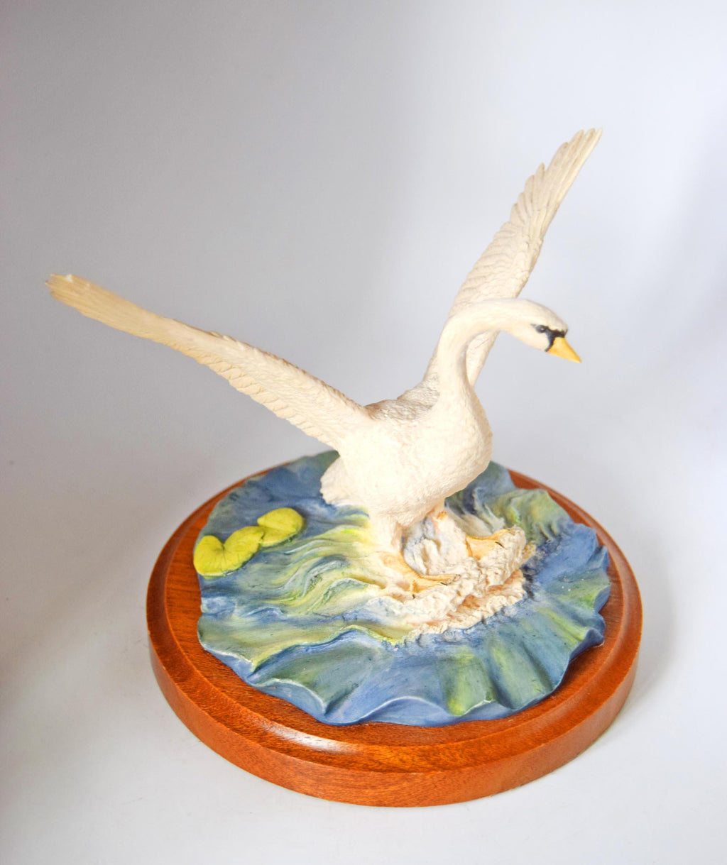 Decorative sculpture of a swan on a wooden base with a water scene