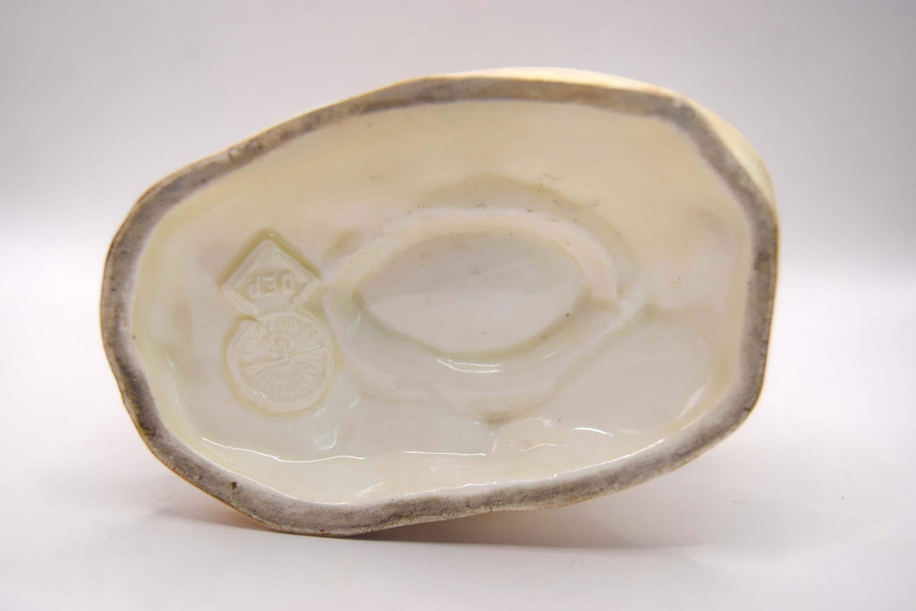 White ceramic dish with a raised logo design on a white background