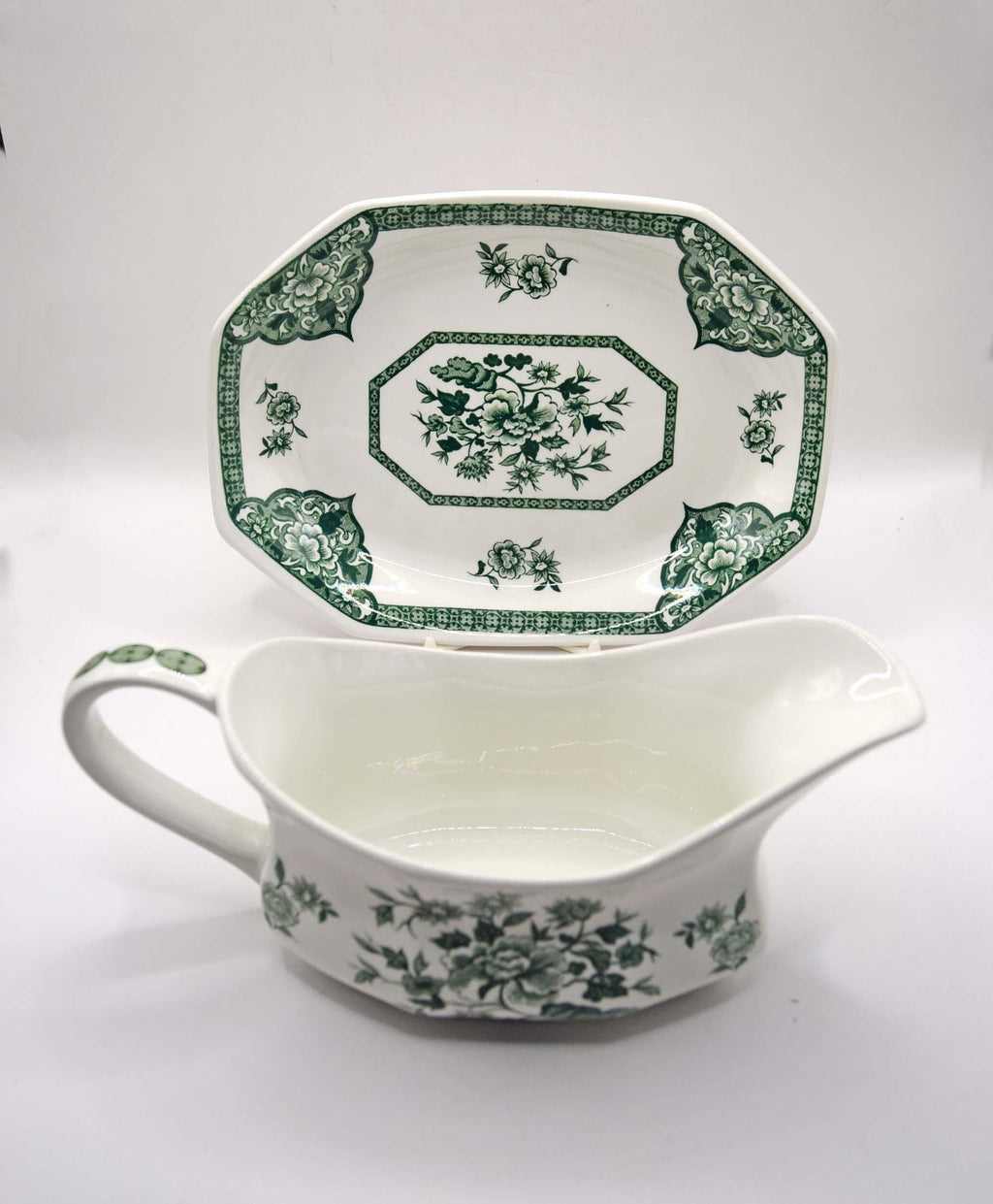 White ceramic gravy boat with green floral pattern on a white background