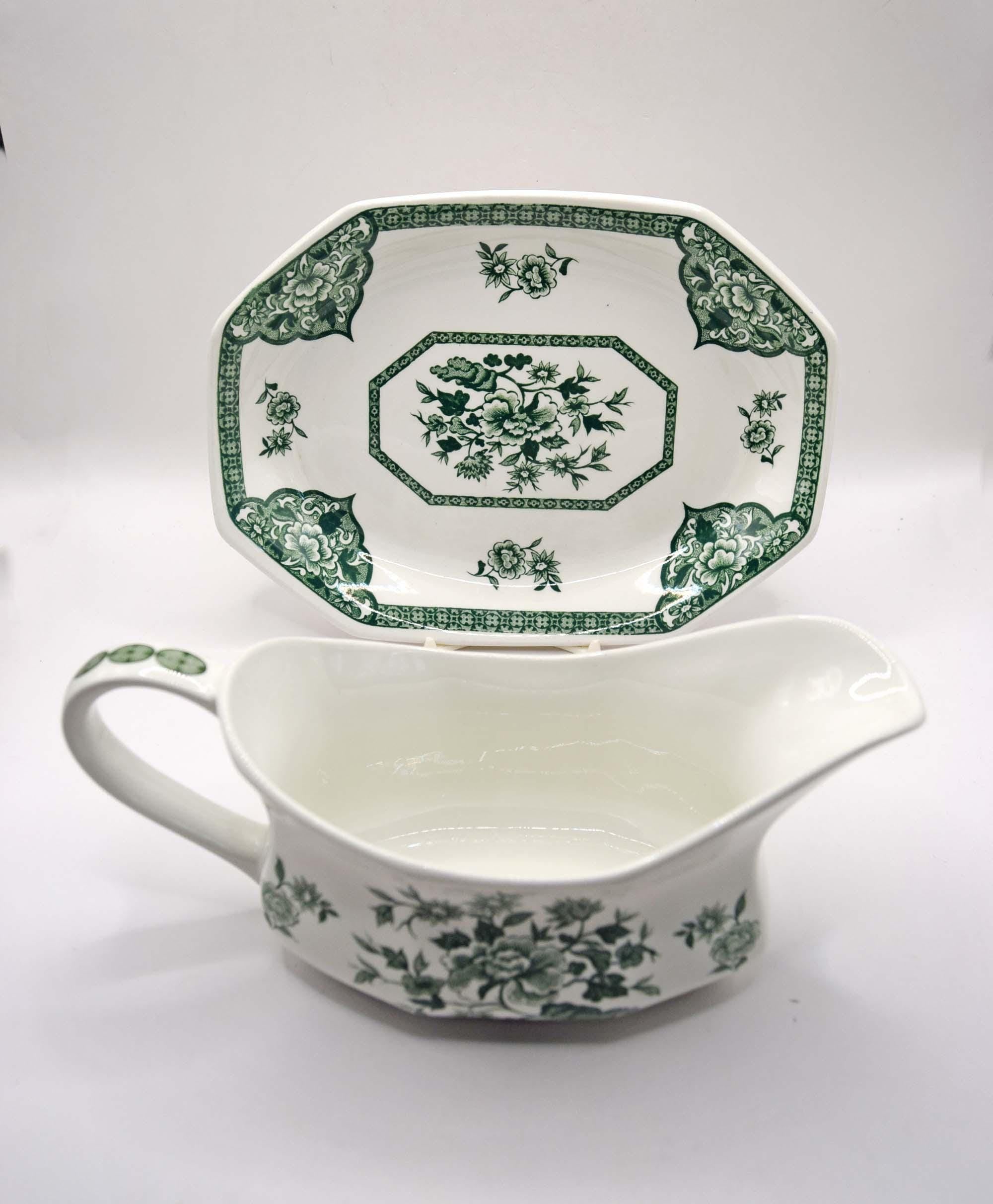 White ceramic gravy boat with green floral pattern on a white background
