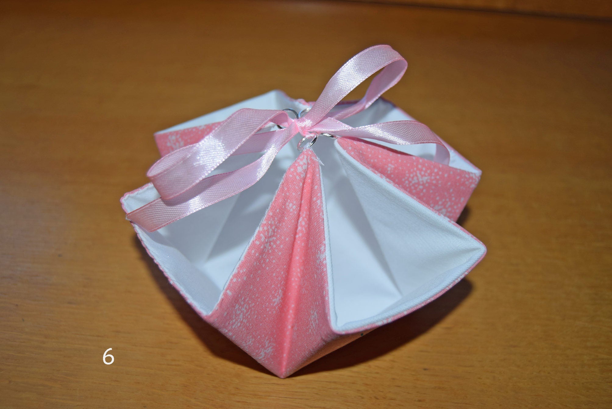 Pink handcrafted gift basket or box with a ribbon on a wooden surface