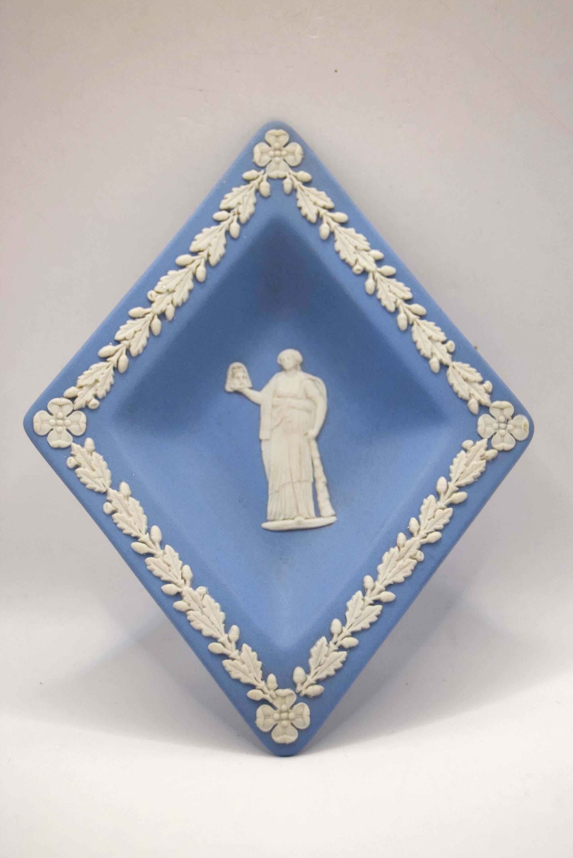 Decorative blue Wedgwood dish with white relief sculpture and floral border on a white background