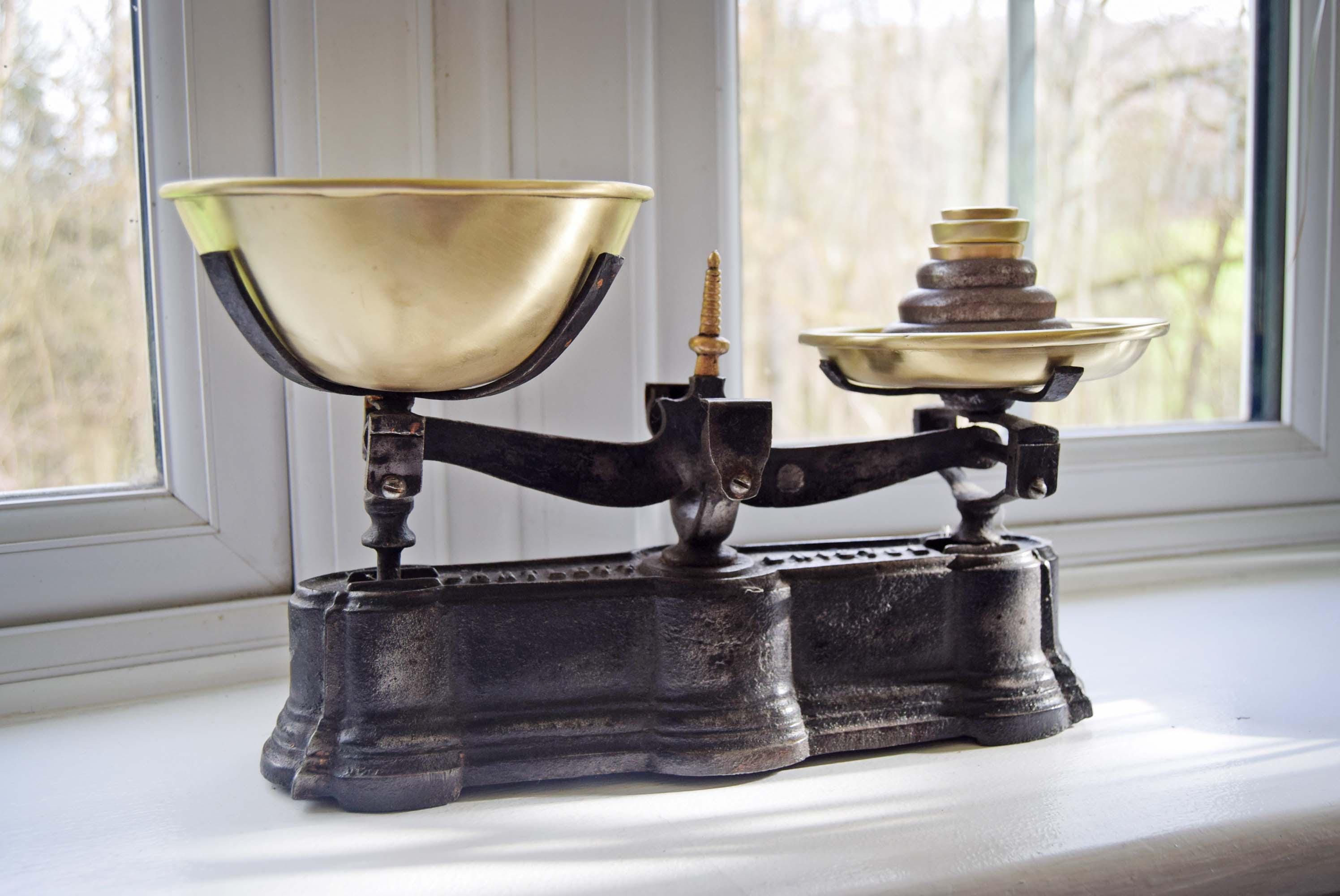 Vintage kitchen scale on a windowsill with a blurred outdoor background