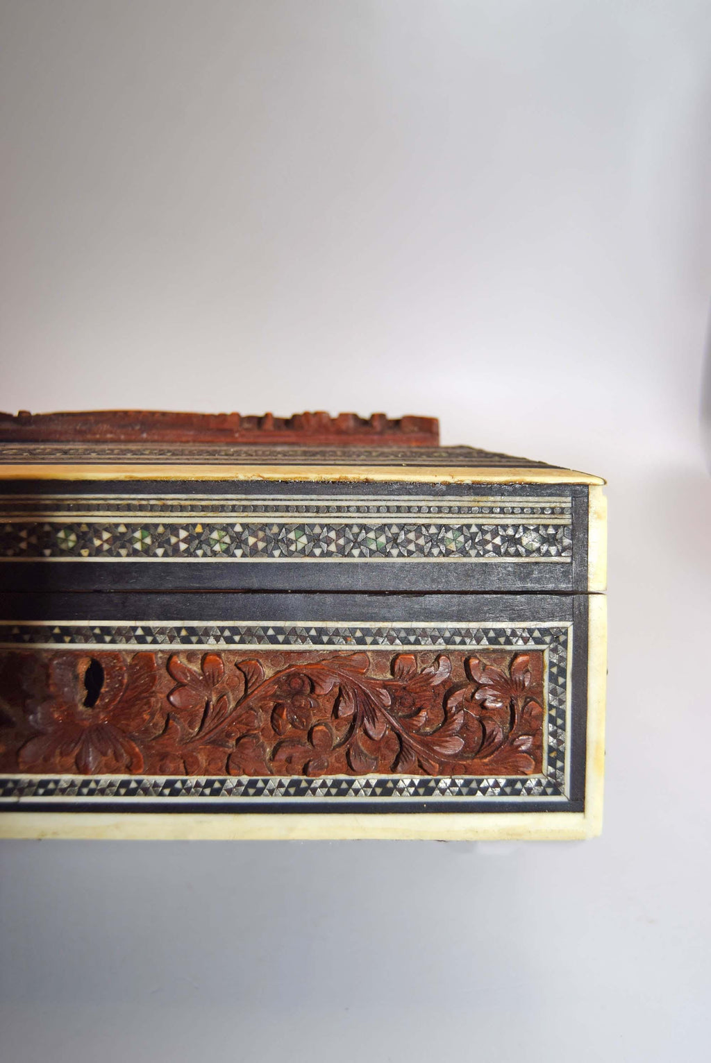 Decorative wooden box with intricate carvings on a white background