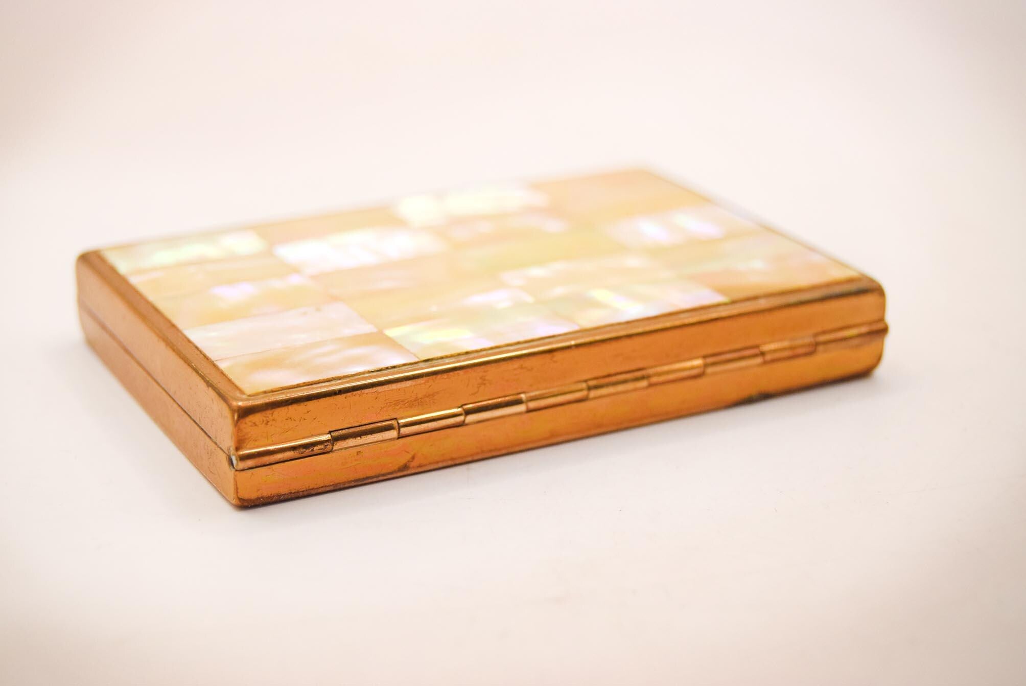 1950s vintage powder compact from AGME Switzerland, featuring a stunning mother-of-pearl lid and golden-tone brass interior.