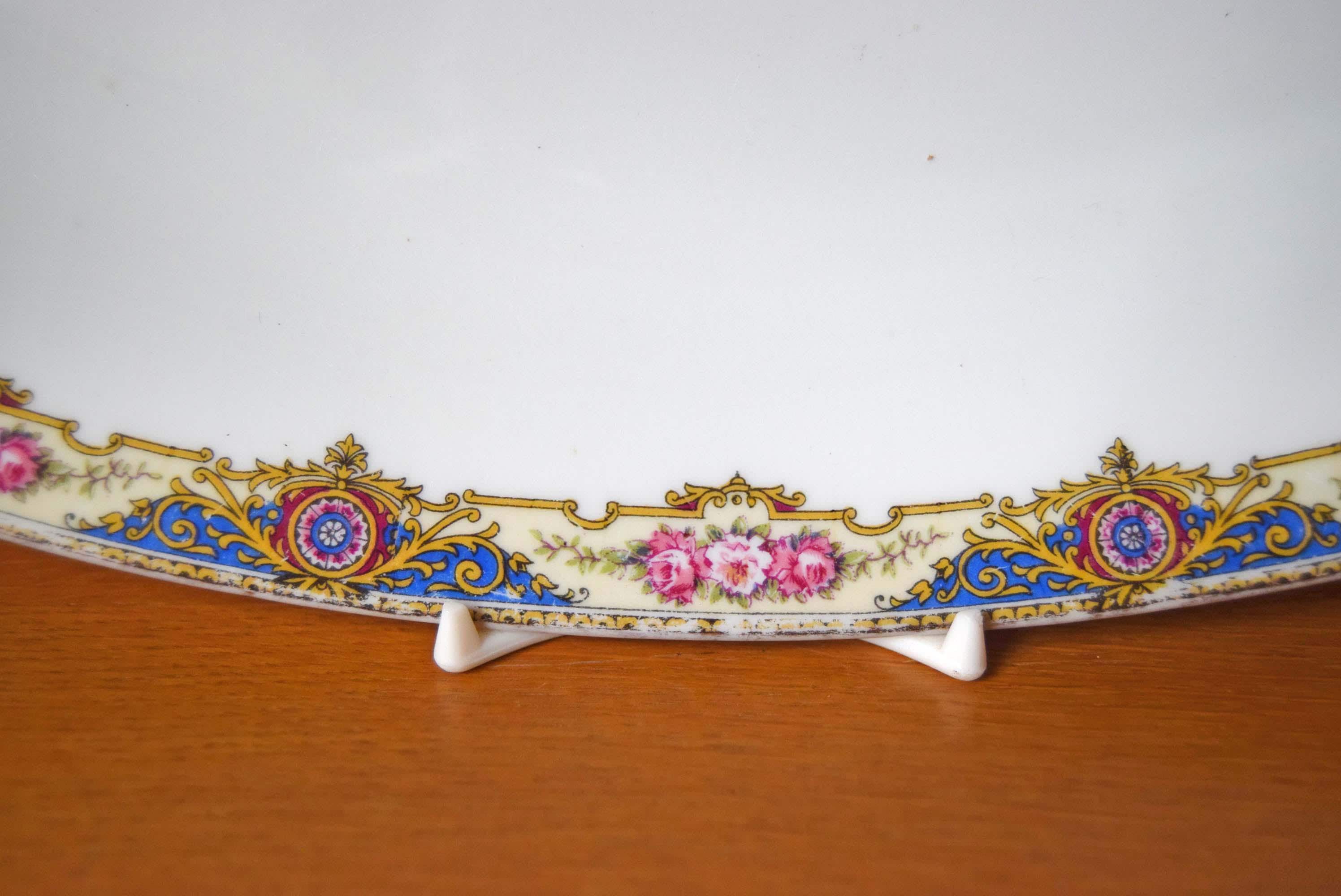 Decorative ceramic plate with floral and gold patterns on a stand against a white background