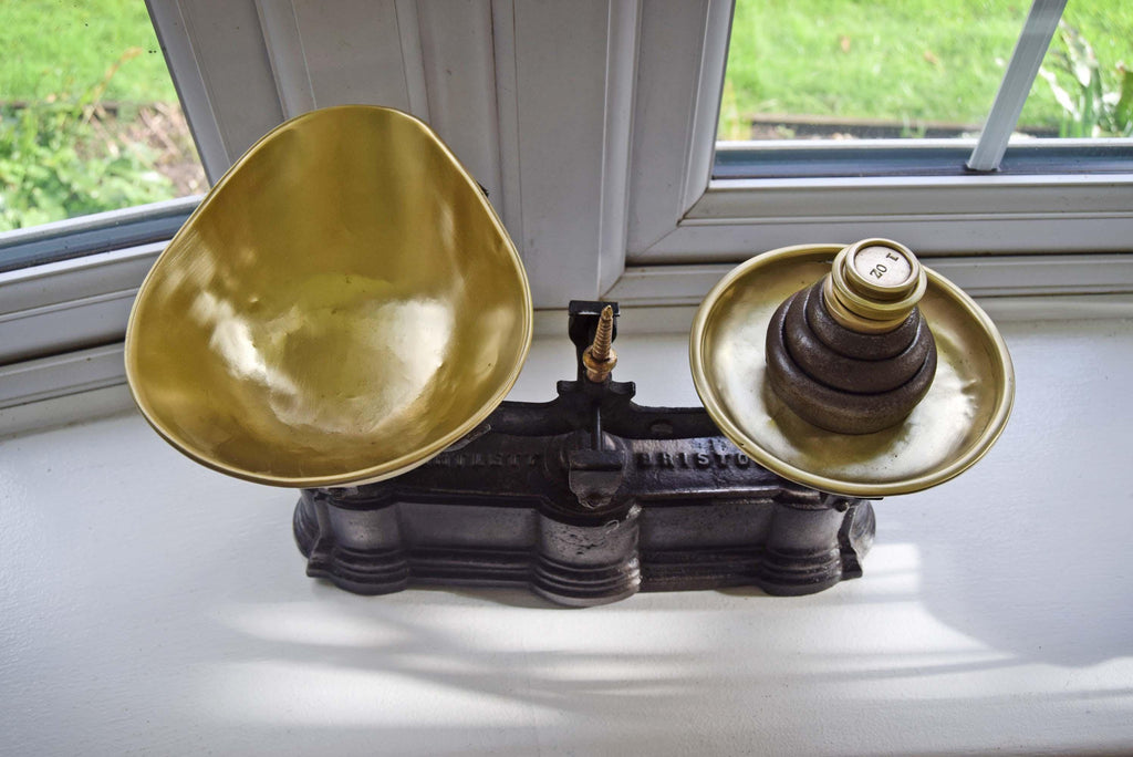 Vintage scale with two gold bowls on a white surface near a window