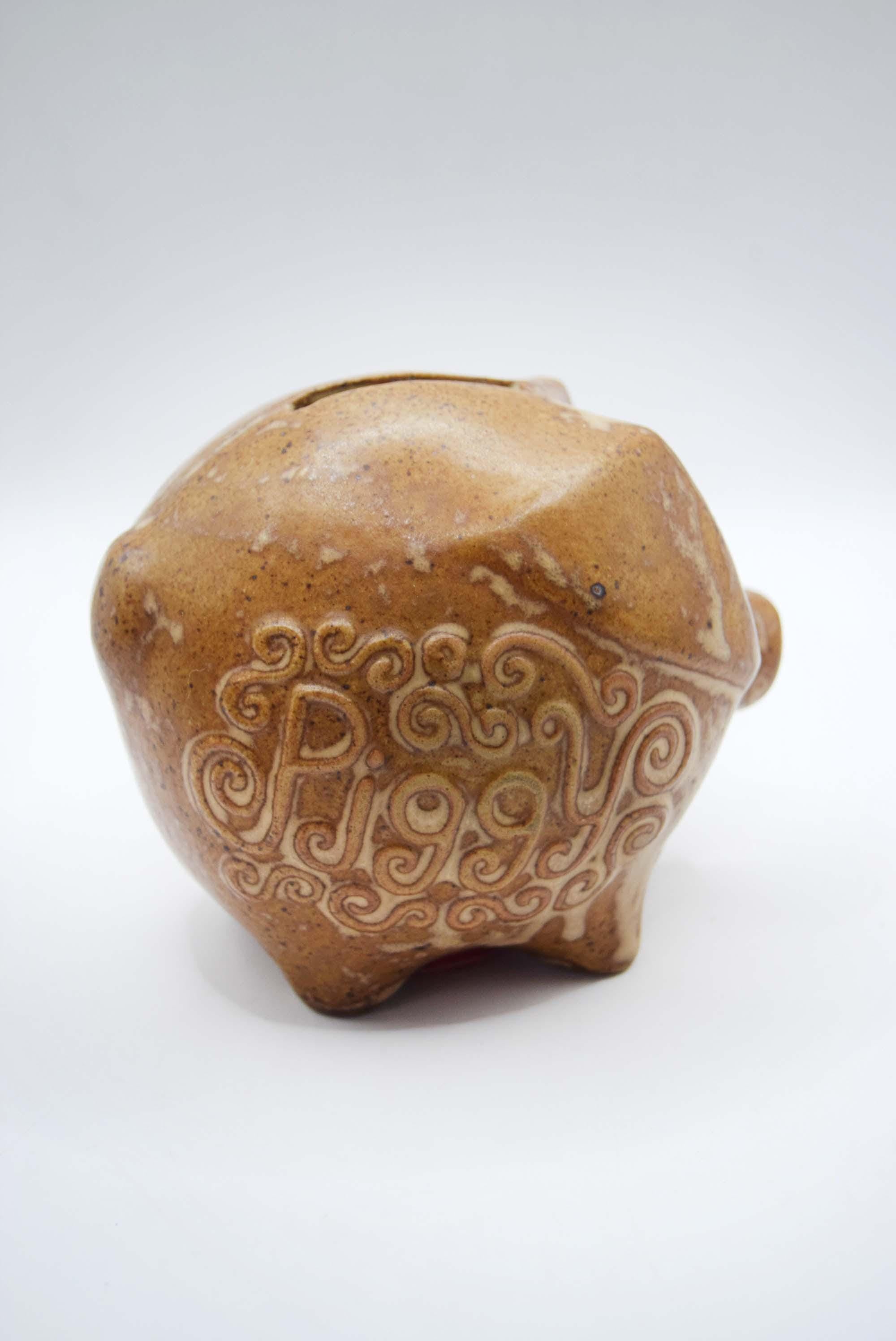 Brown ceramic piggy bank with decorative design on a white background