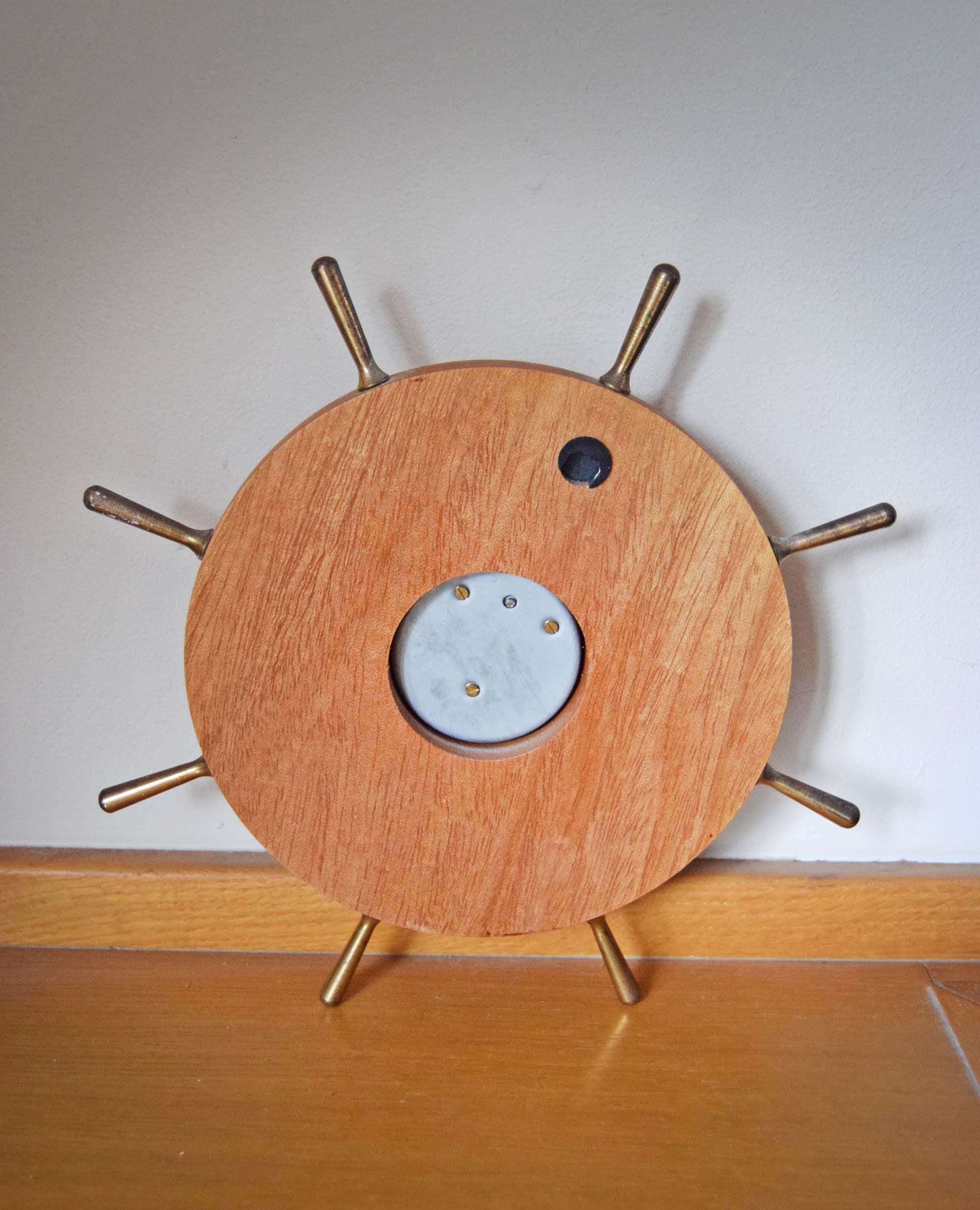 Wooden ship's wheel with brass spokes on a white wall