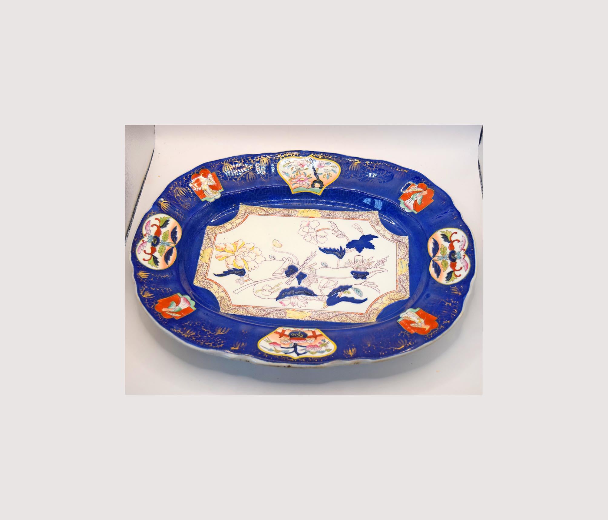 Decorative ceramic platter with blue border and colorful central design on a white background