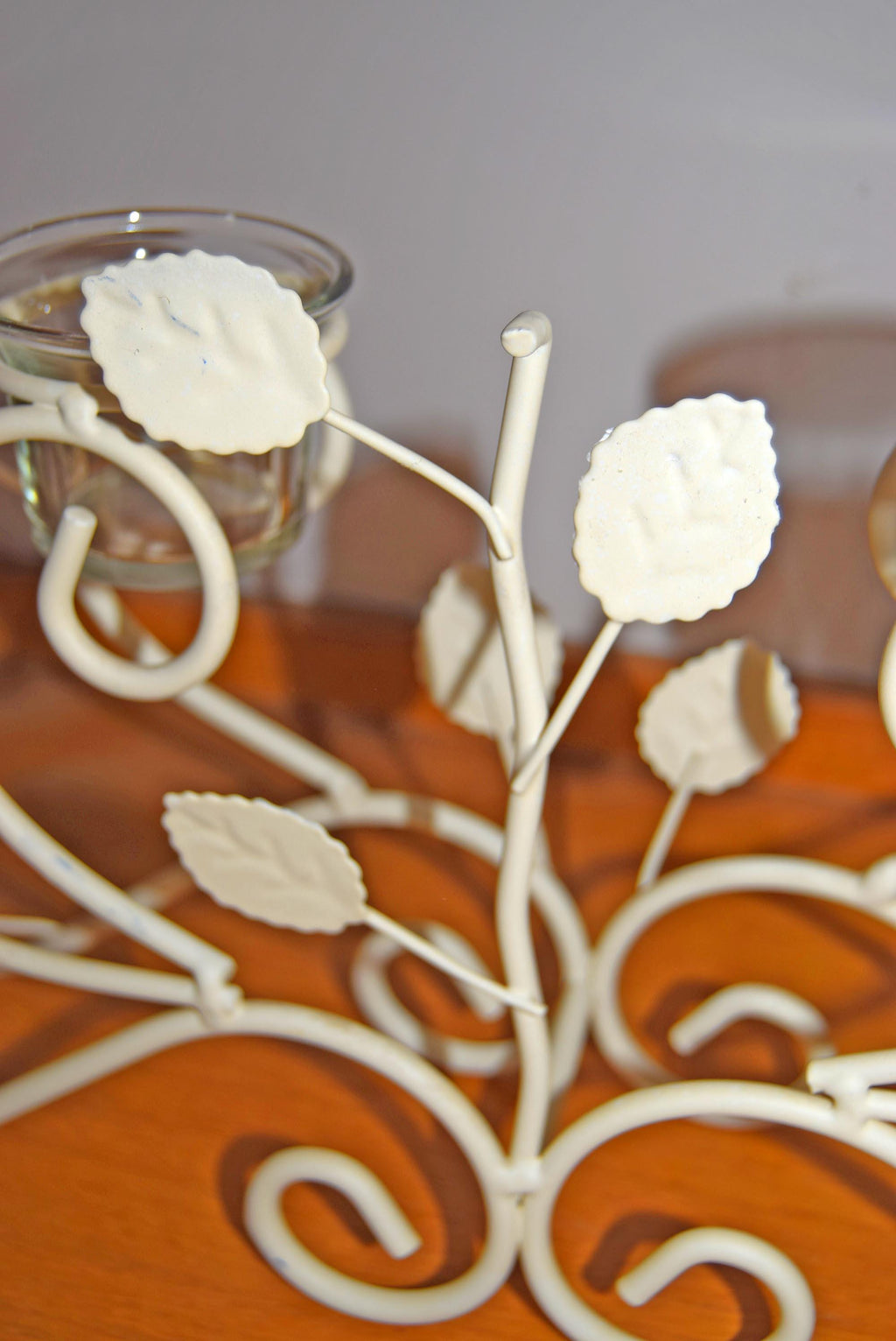 Decorative metal branch with white flowers on a wooden surface