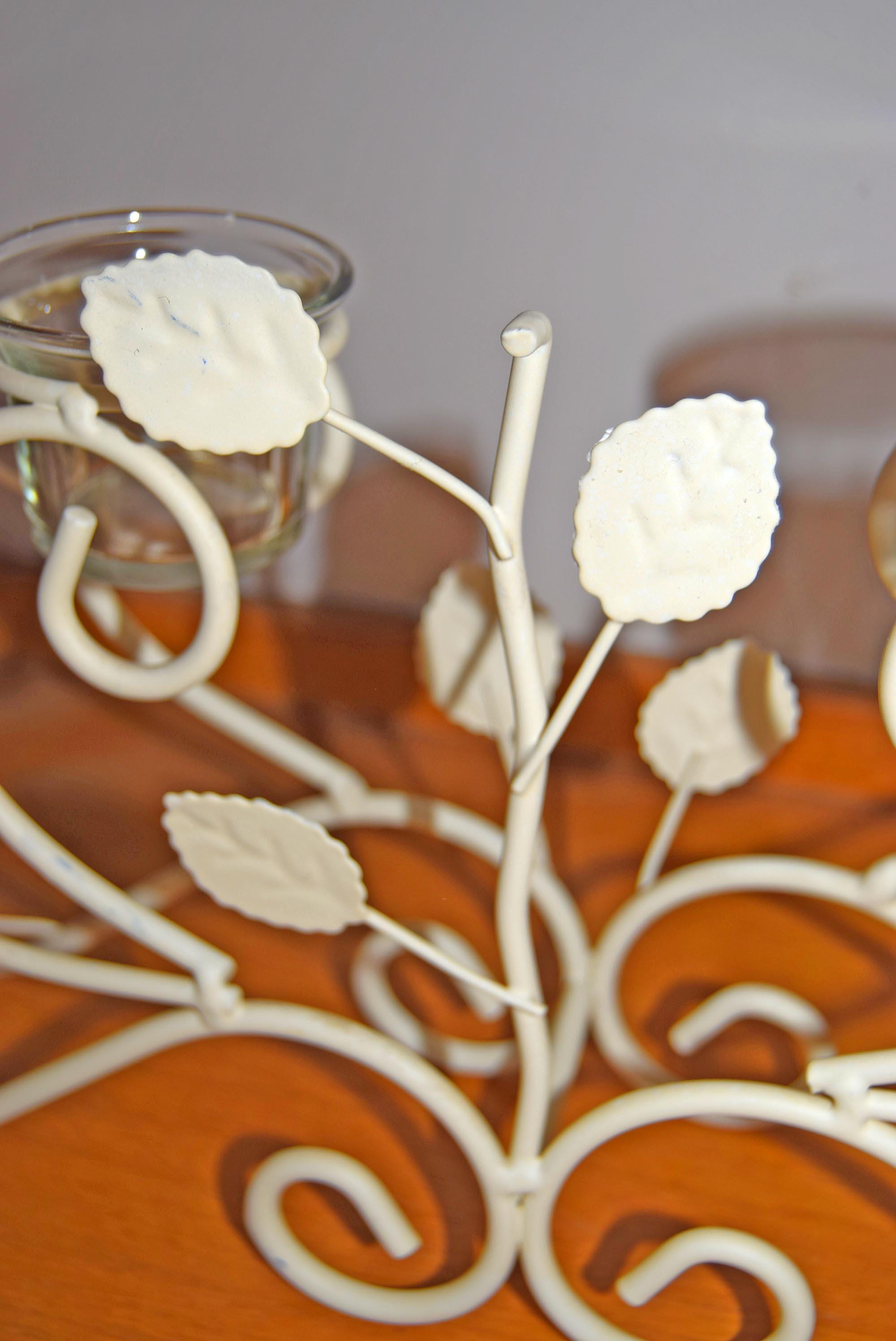 Decorative metal branch with white flowers on a wooden surface