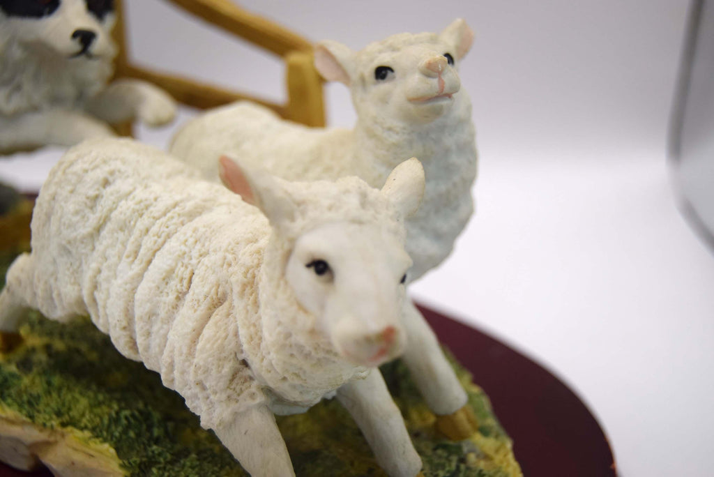 Vintage Juliana Collection figurine depicting a black and white collie sheep dog chasing two sheep.