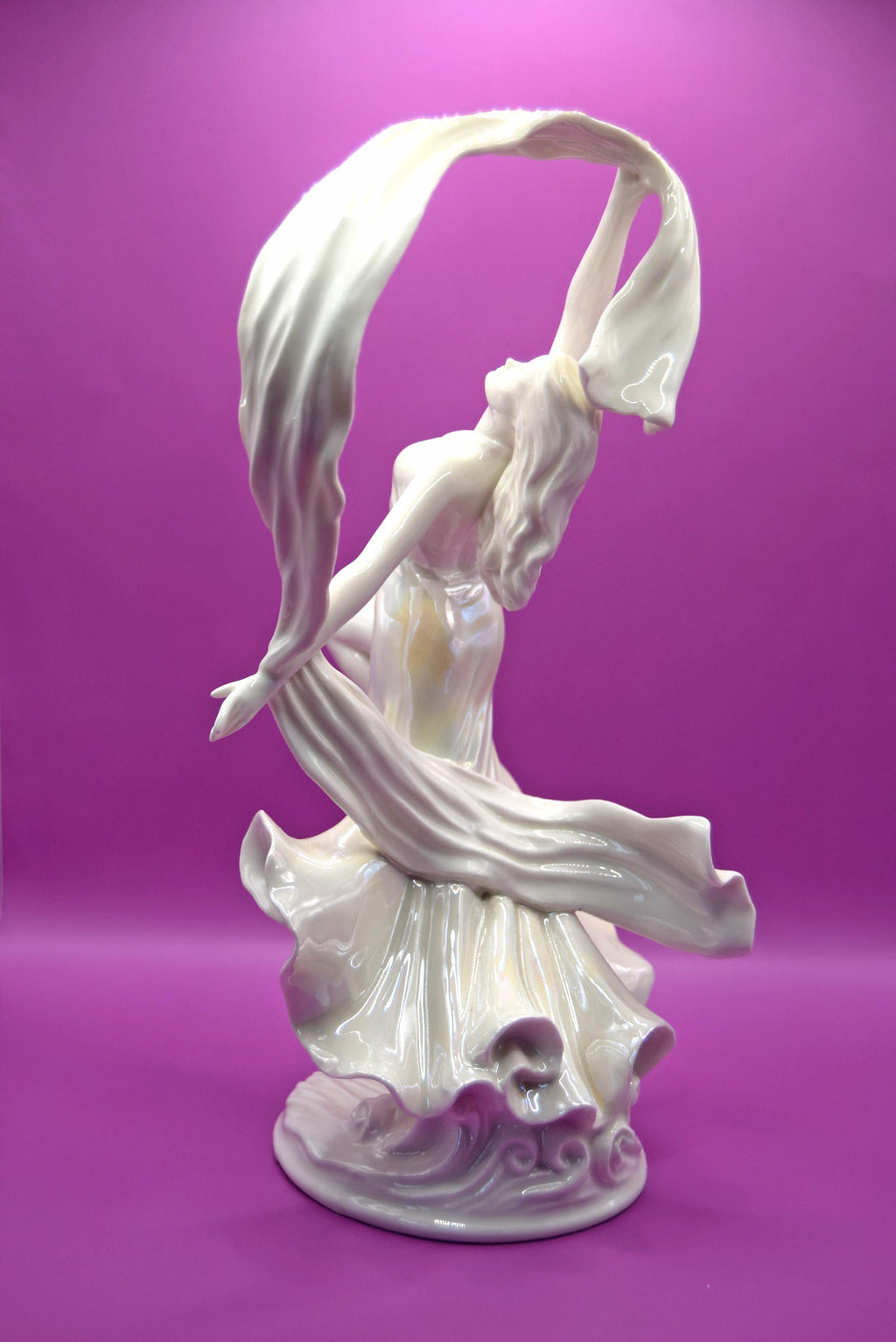 White ceramic sculpture of a dancer with flowing fabric against a purple background
