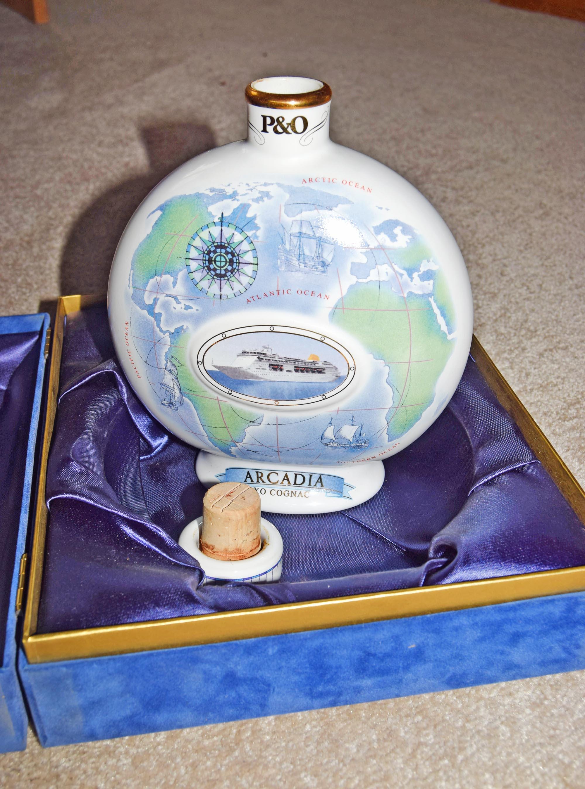Decorative bottle with world map design and 'P&O' branding, placed on a purple cushion.