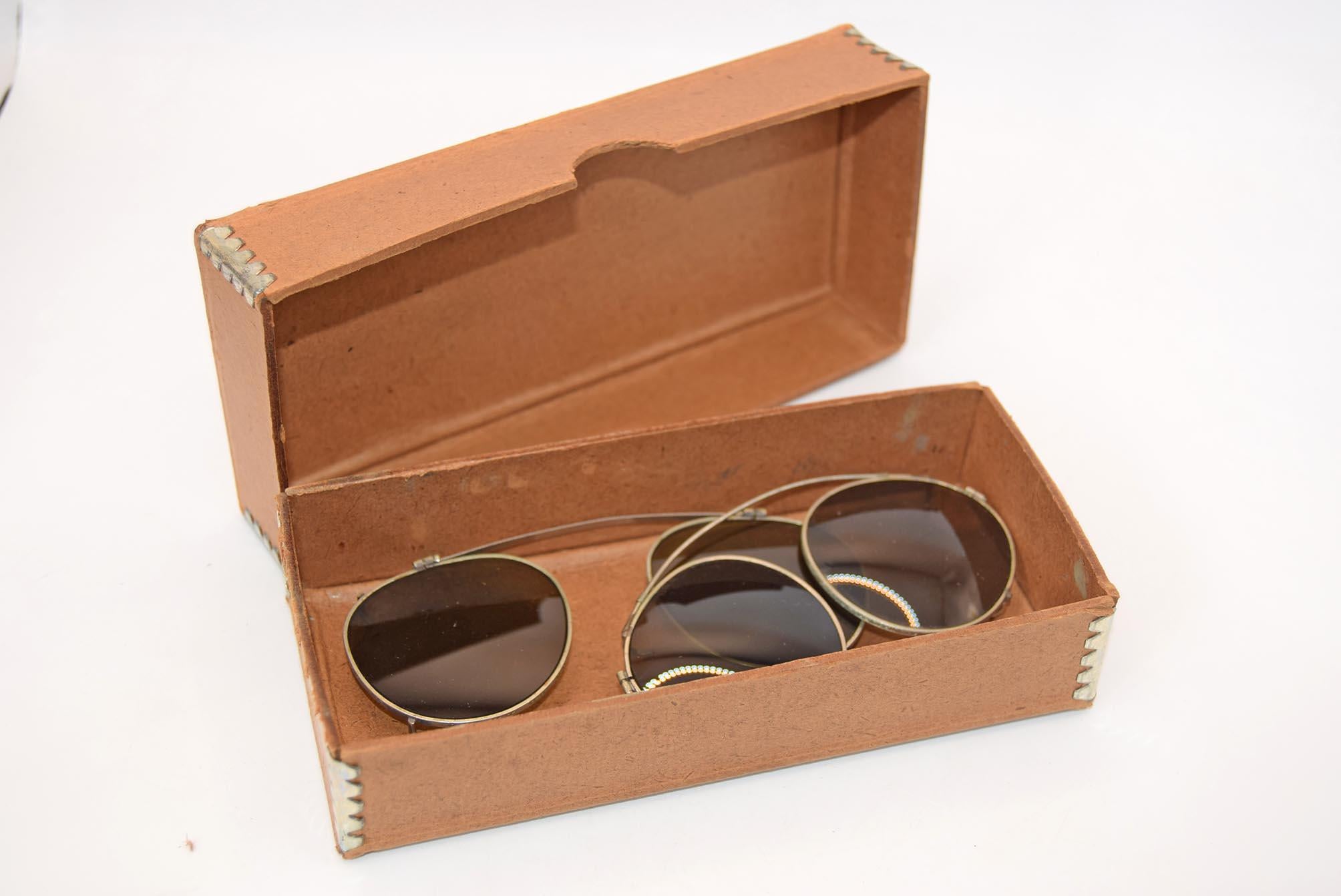 Brown sunglasses in an open cardboard box on a white background