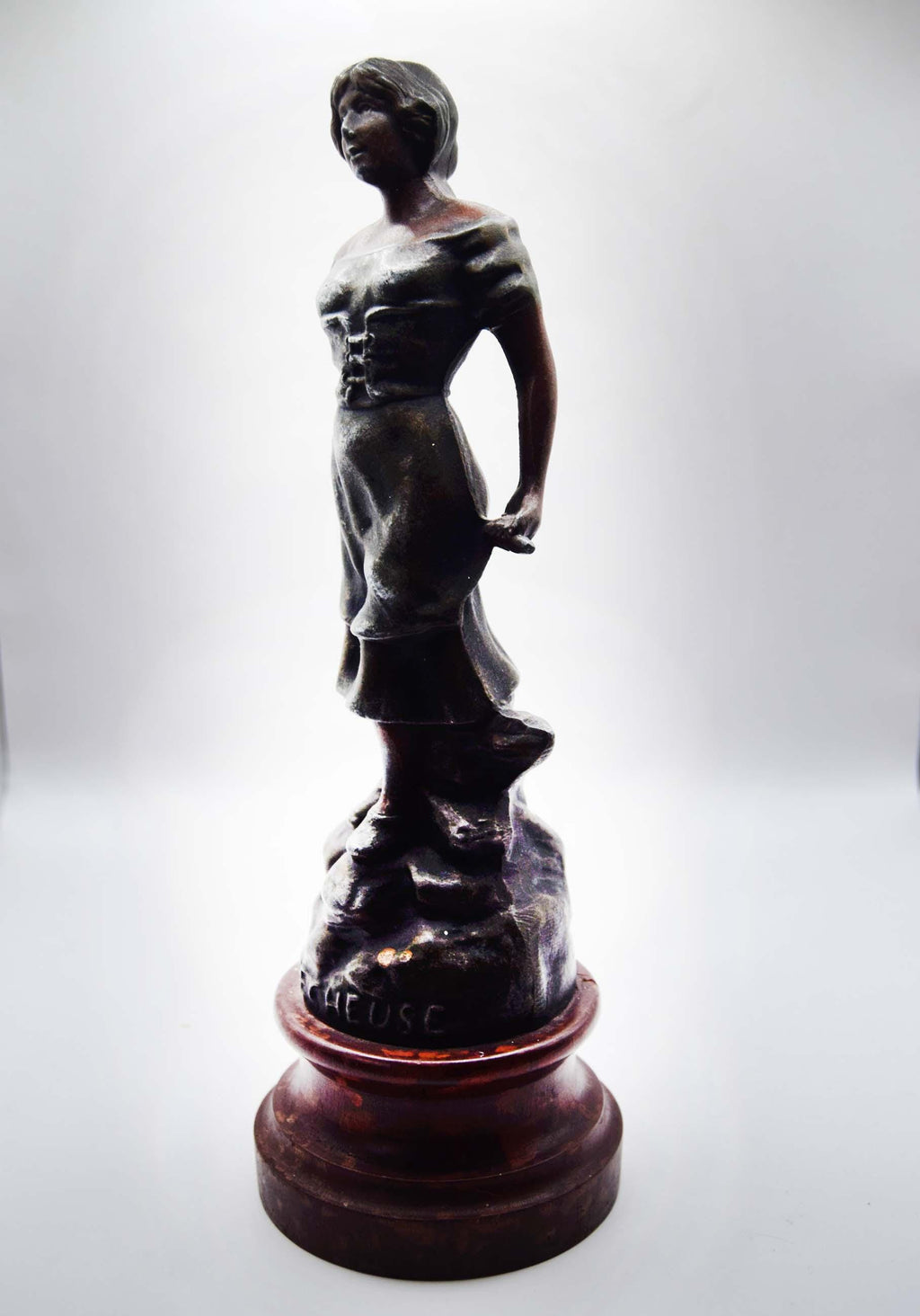 Bronze statue of a figure on a white background