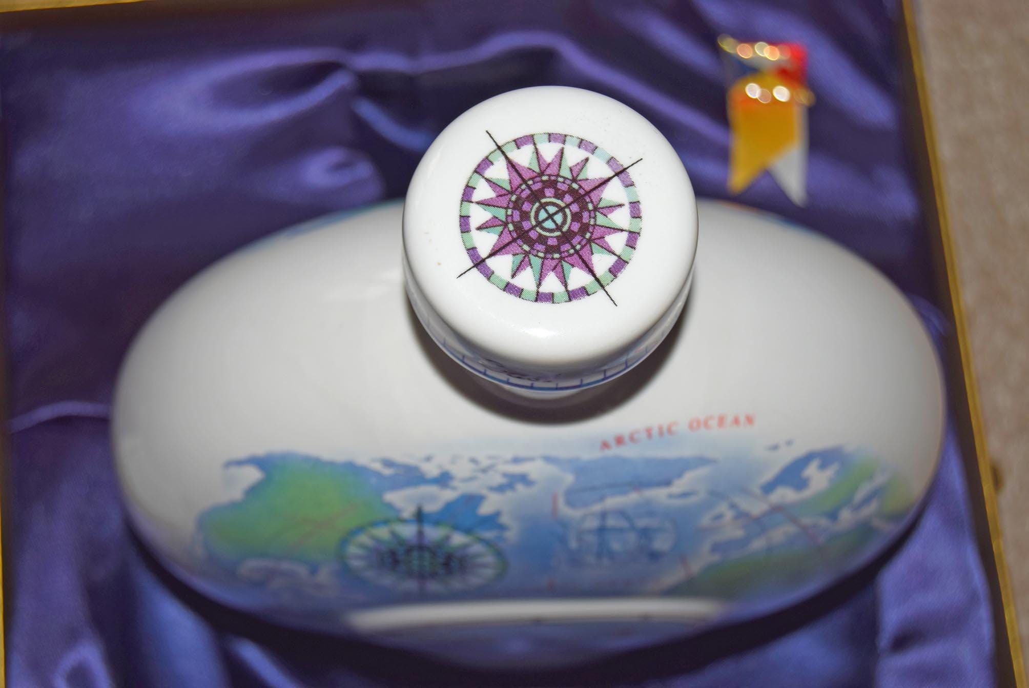 Ceramic container with a lid featuring a world map design on a purple fabric background.