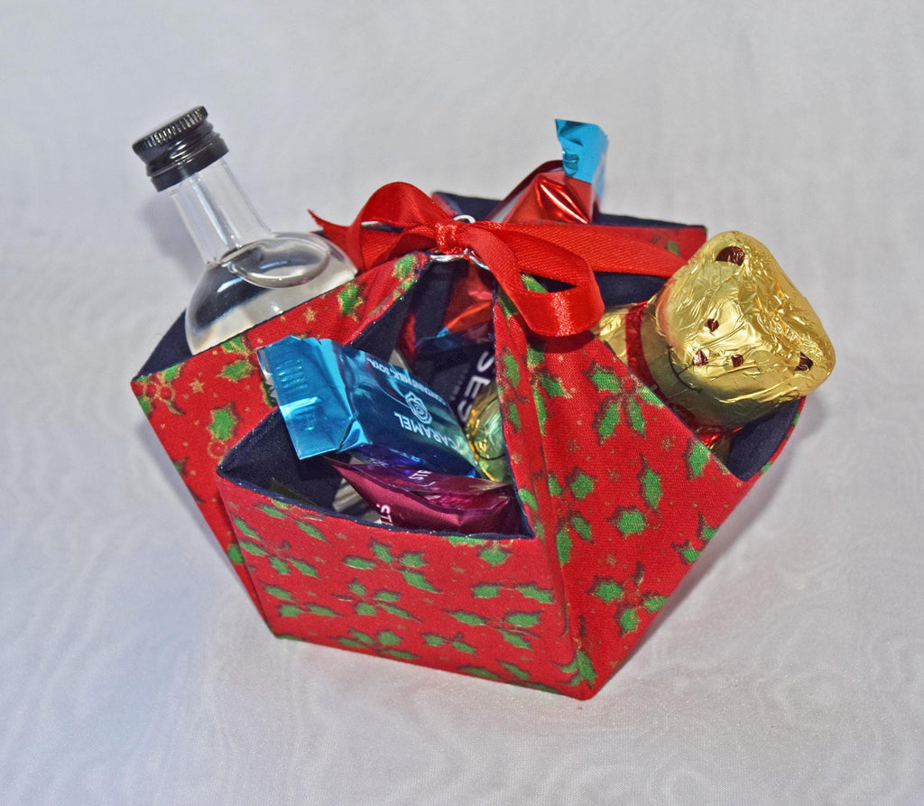 Decorative gift box with a bottle, chocolates, and a gold candy on a white background