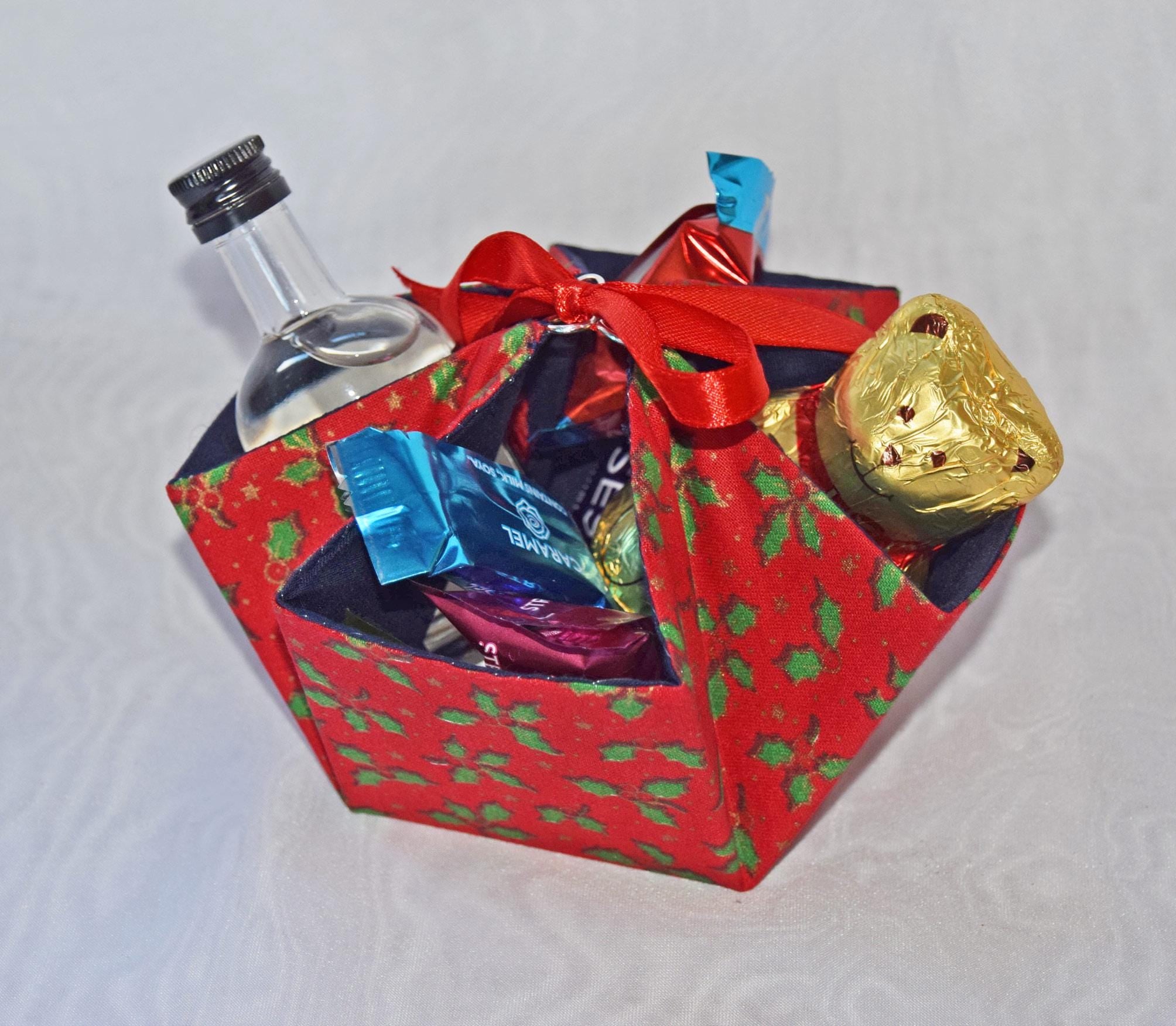 Decorative gift box with a bottle, chocolates, and a gold candy on a white background