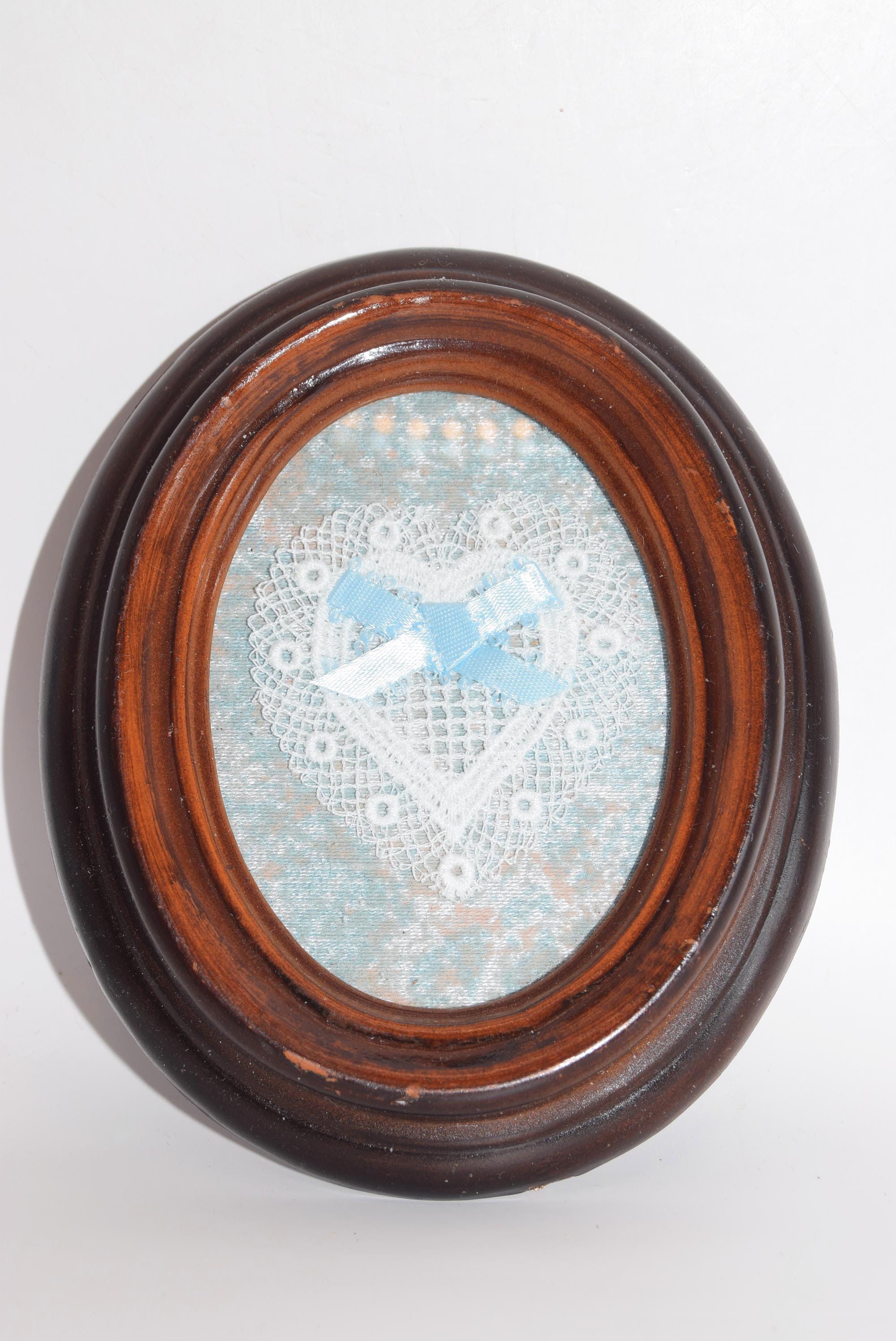 Round wooden frame with a decorative glass panel featuring a blue heart and white cross on a light blue background.