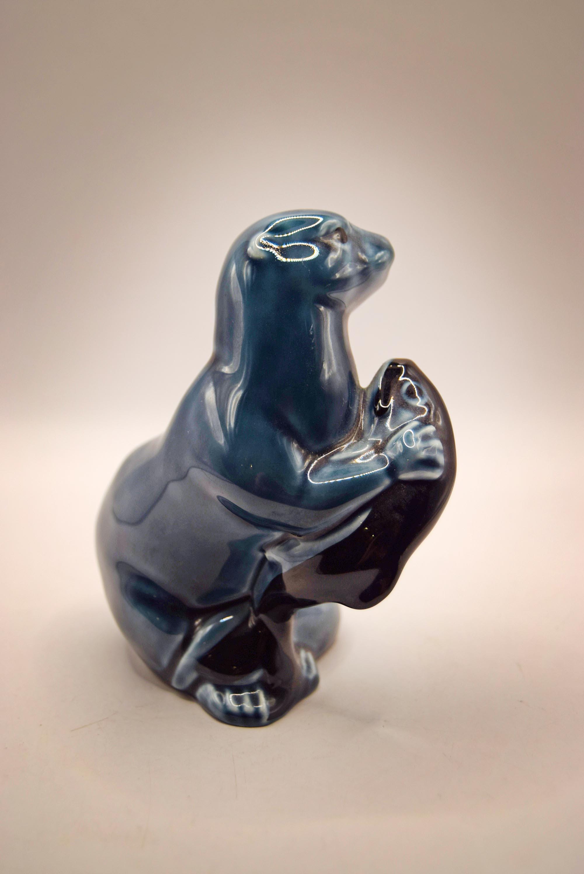 Blue ceramic seal figurine on a beige background