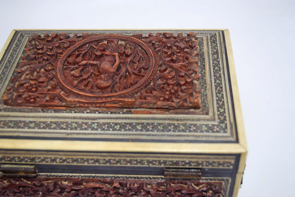 Carved wooden box with intricate patterns on a white background