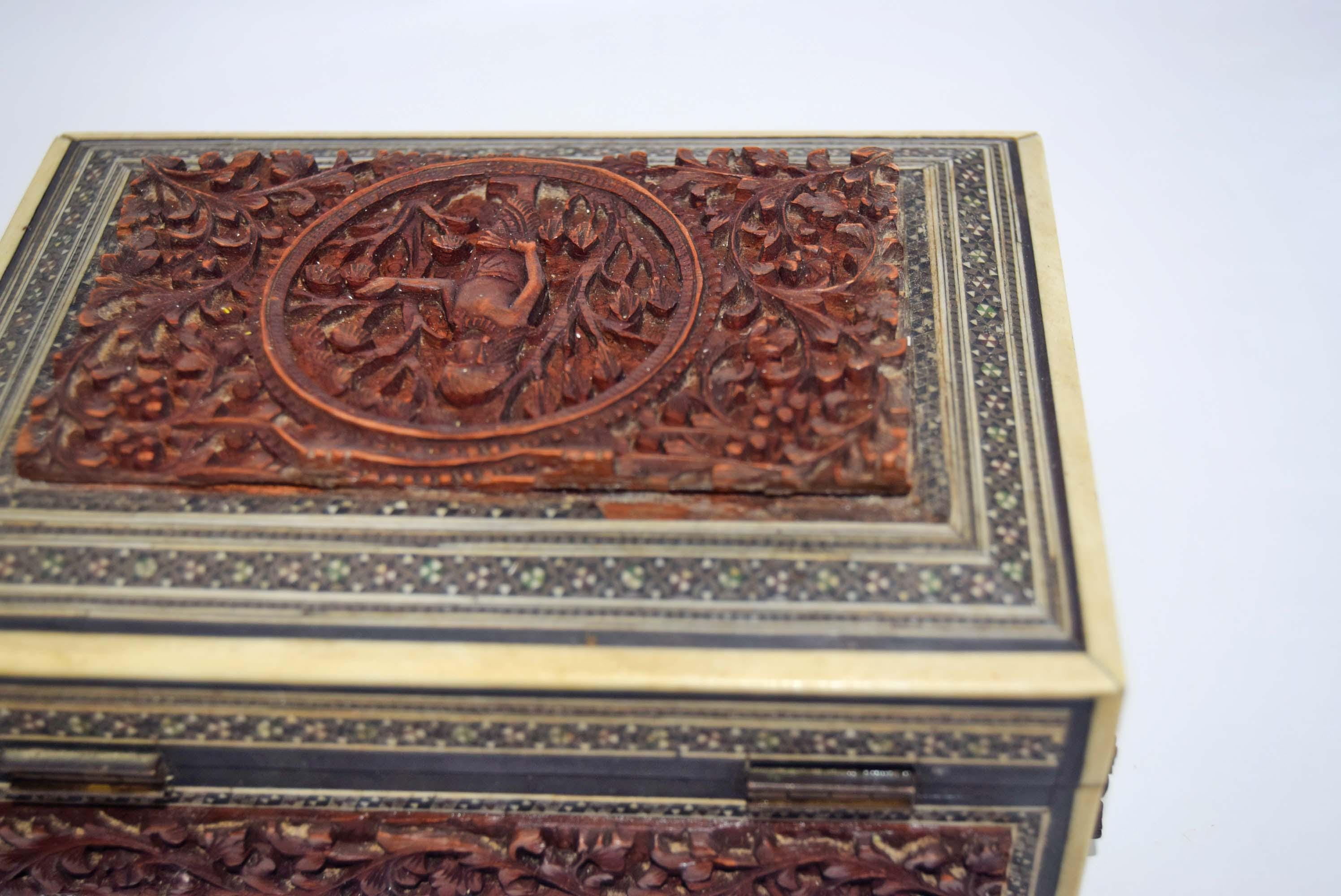 Carved wooden box with intricate patterns on a white background