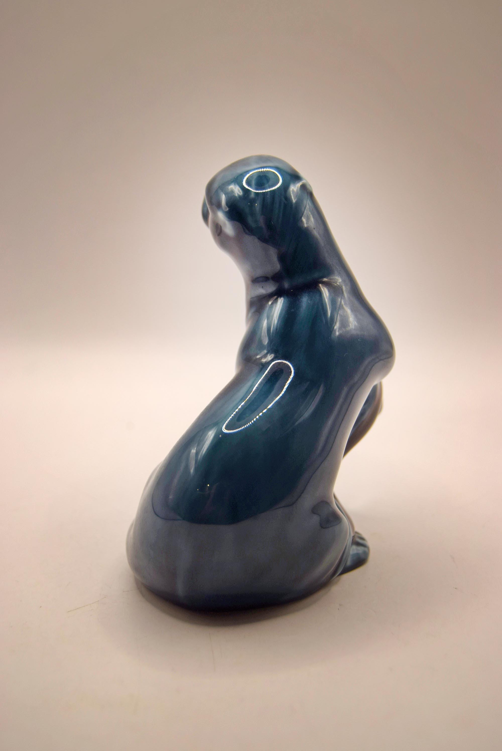 Blue ceramic seal figurine on a beige background