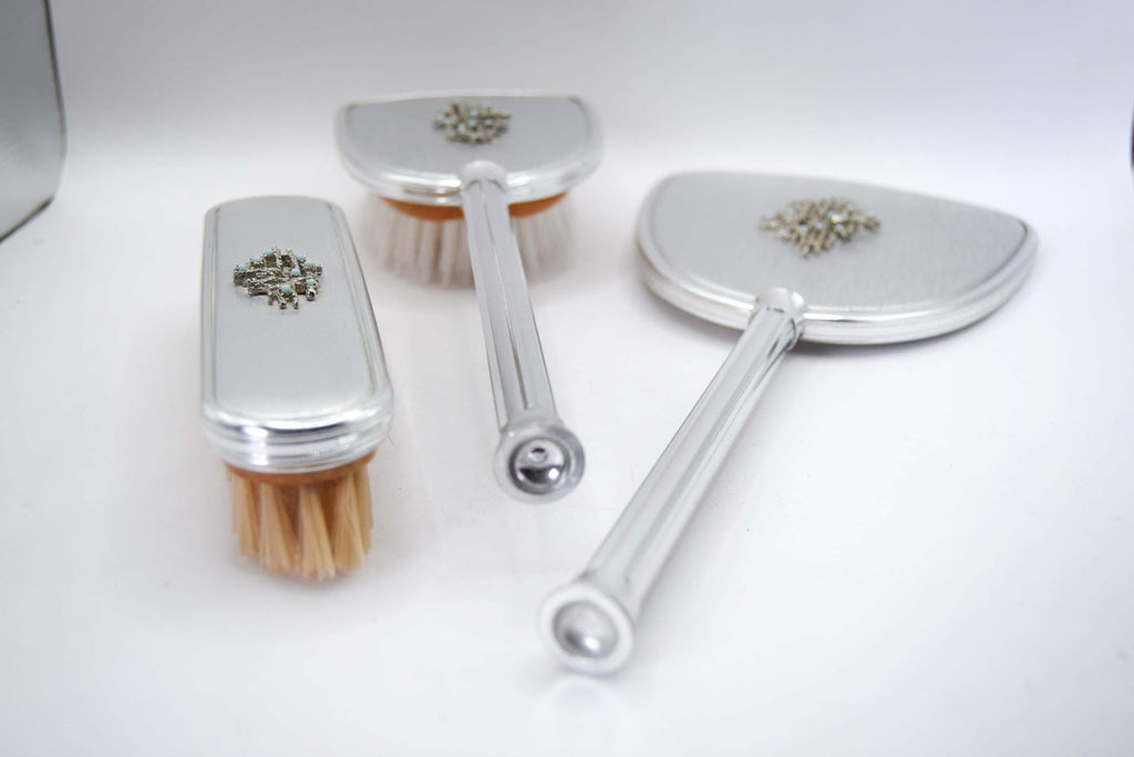 Set of silver hairbrushes and mirror on a white background