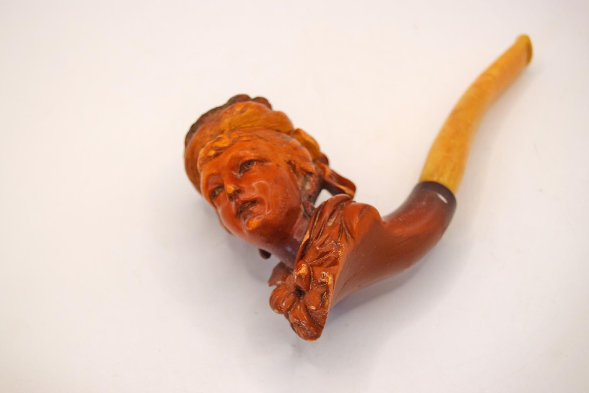 Wooden pipe with a carved face on a white background