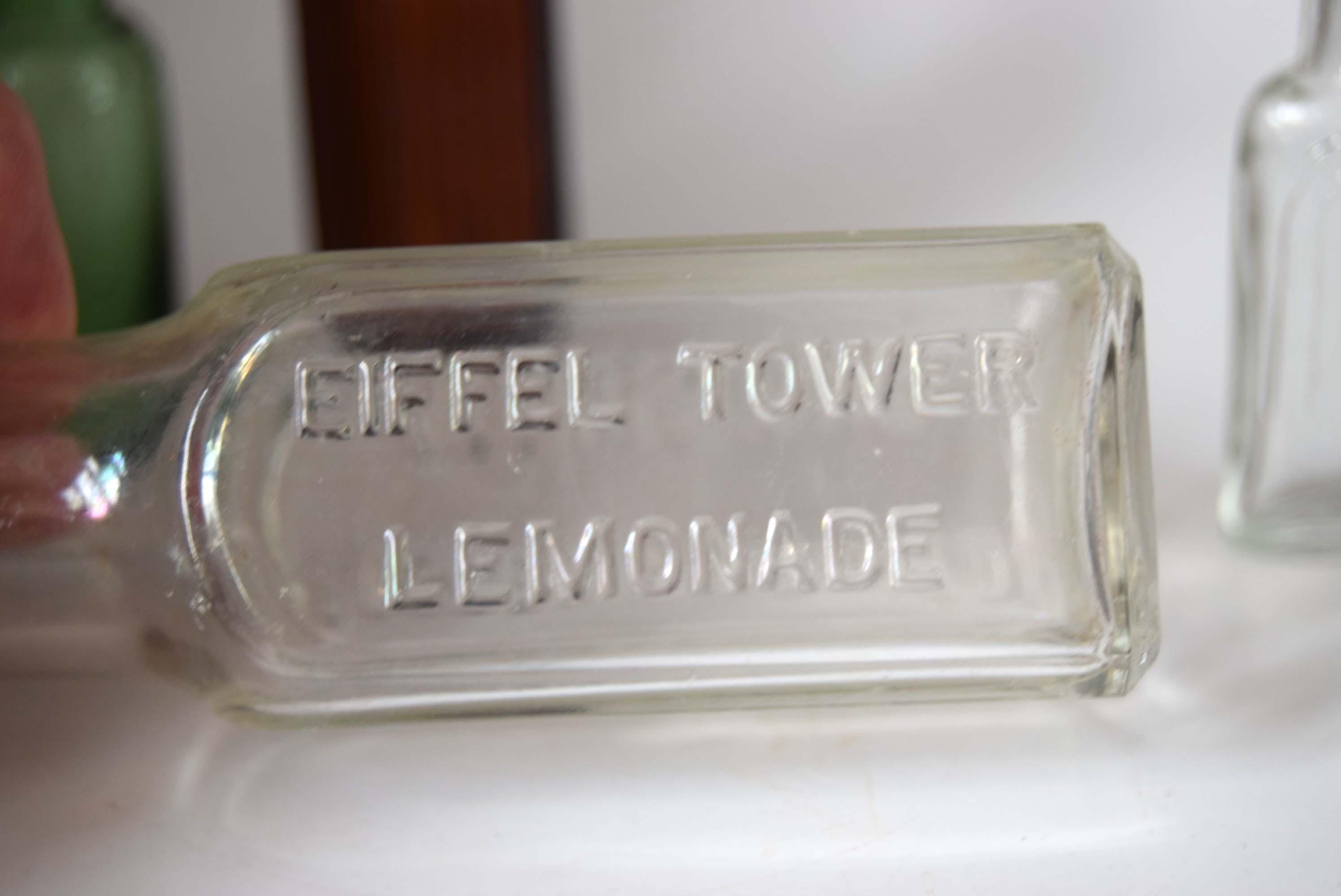 Clear glass bottle labeled 'Eiffel Tower Lemonade' on a white surface.