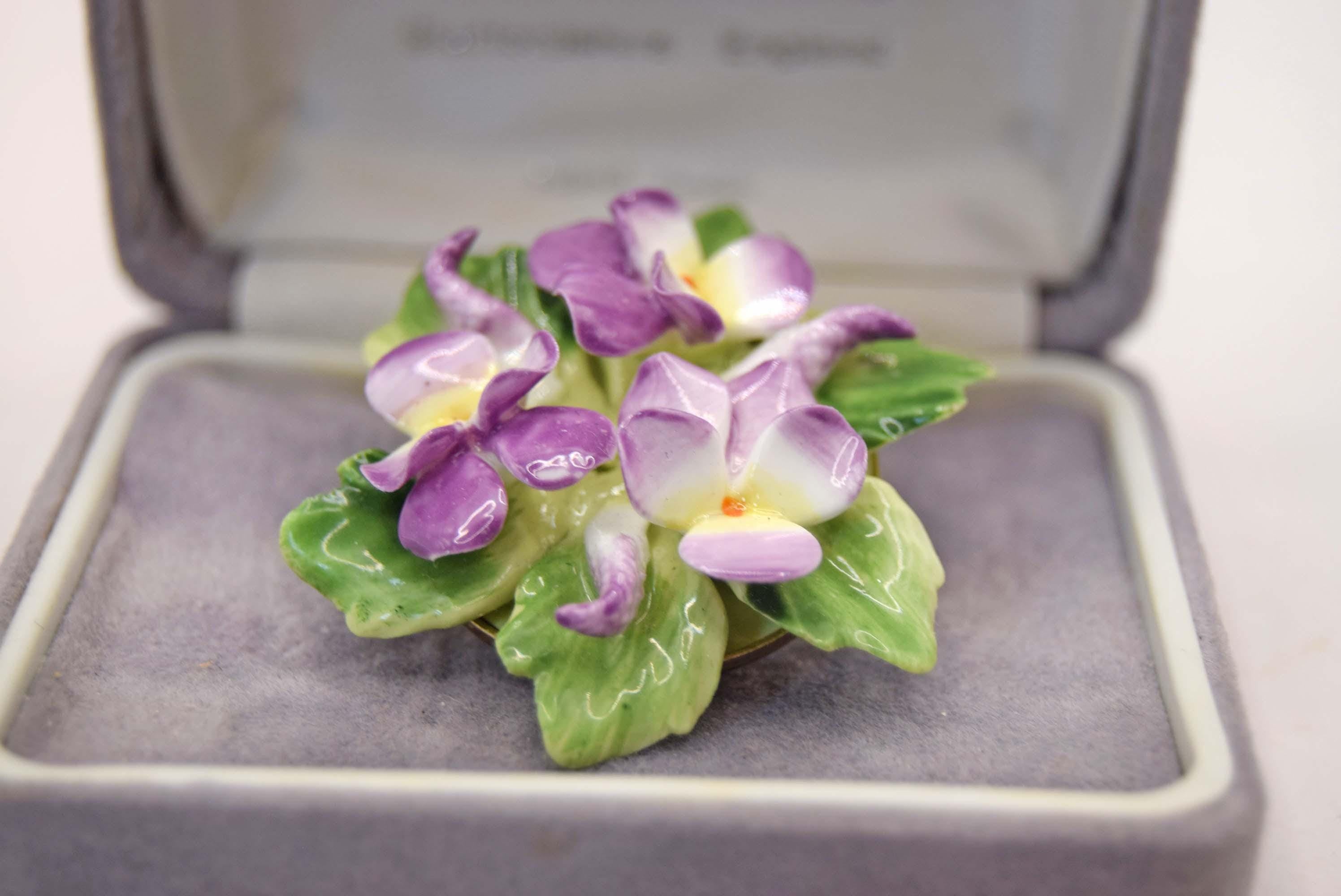 Purple flower brooch in an open jewelry box on a light background