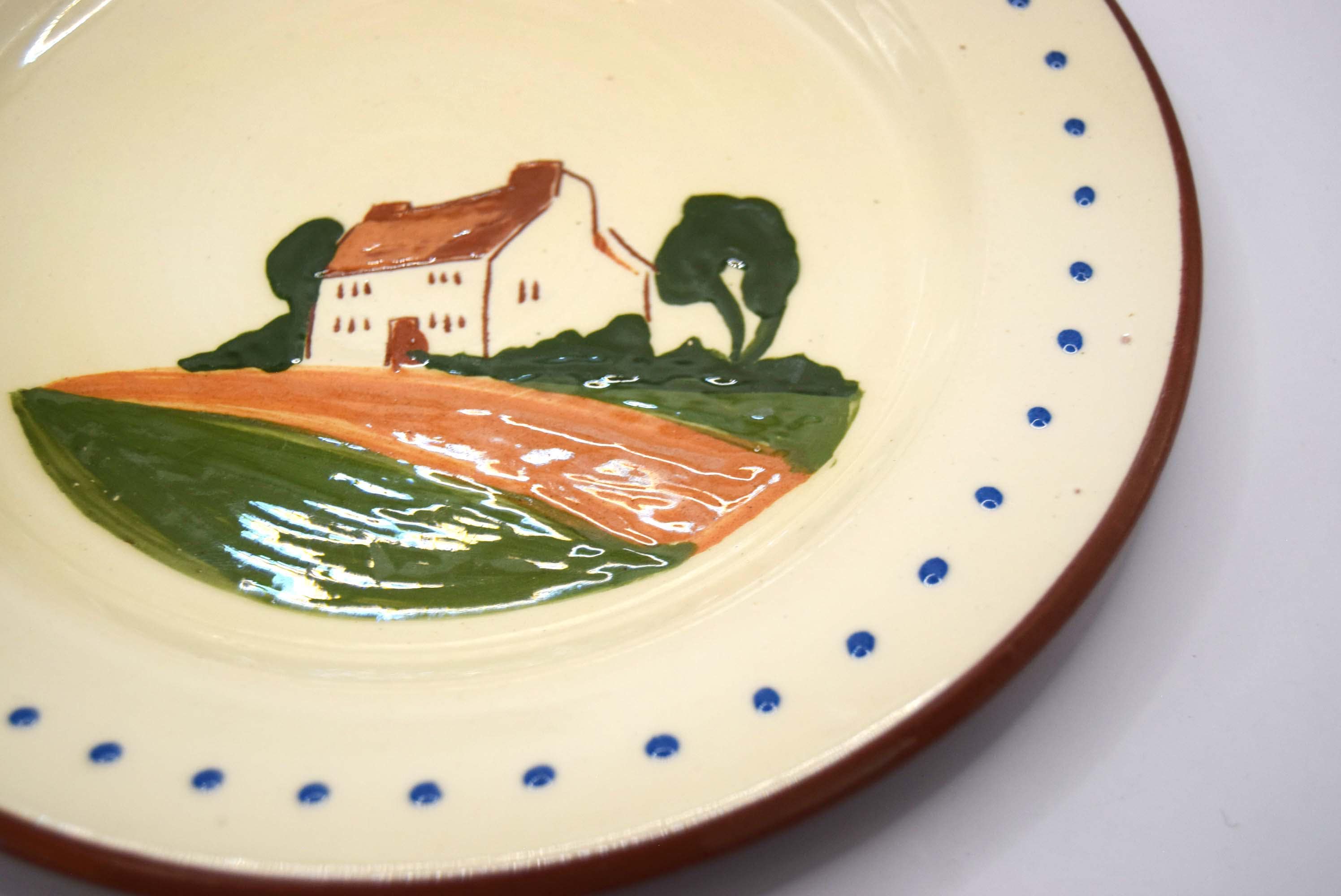 Ceramic plate with a scenic design of a house and landscape on a white background