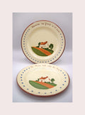Two ceramic plates with scenic designs and text on a light gray background