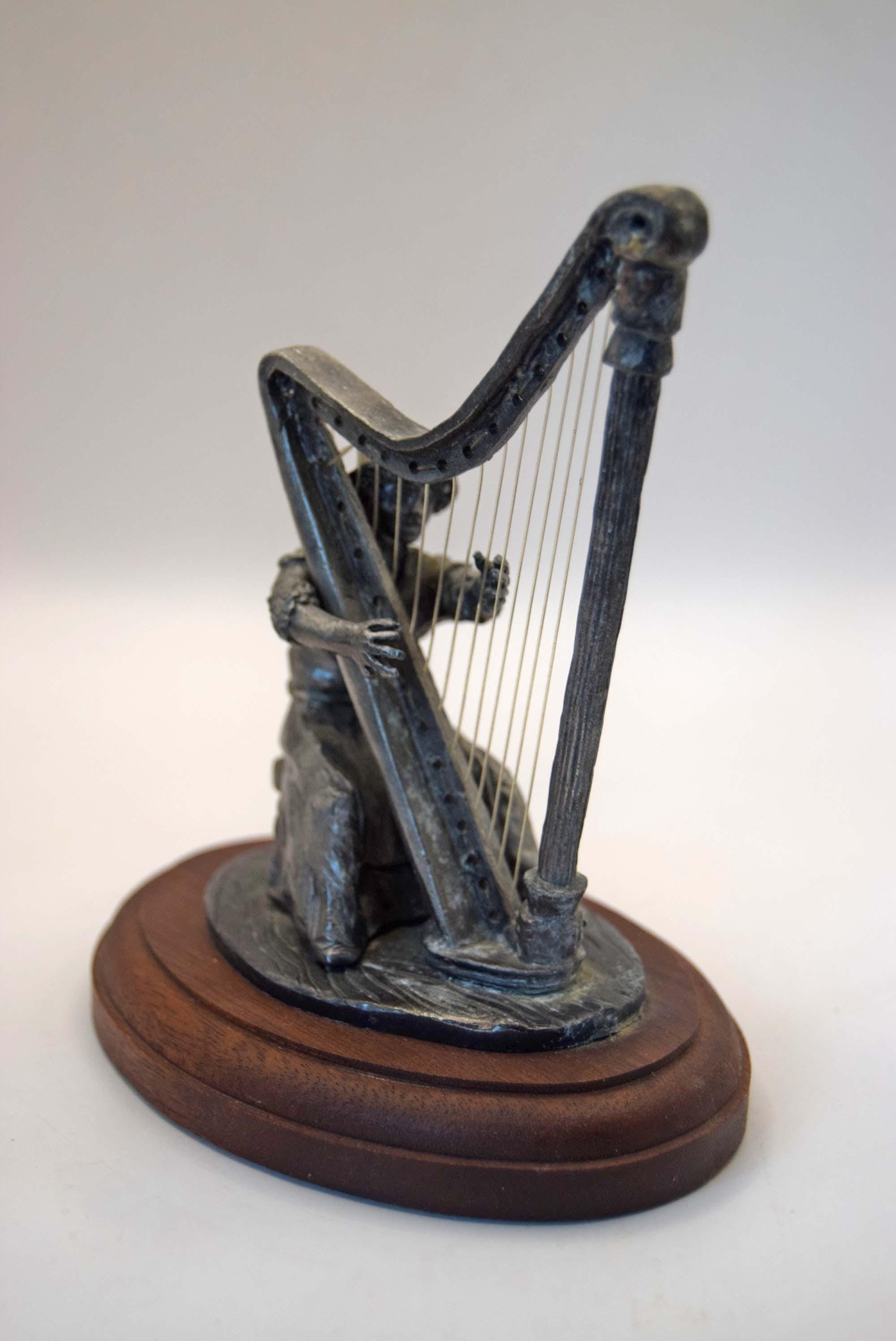Statue of a harp on a wooden base against a white background