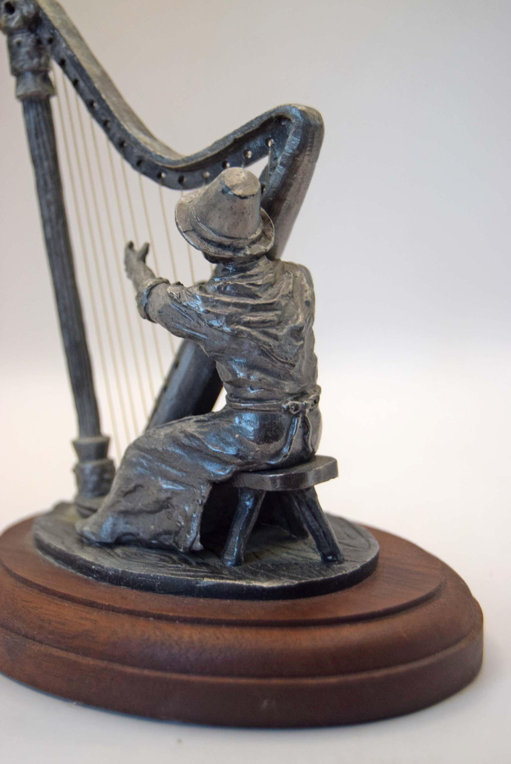 Bronze sculpture of a harpist on a wooden base against a white background