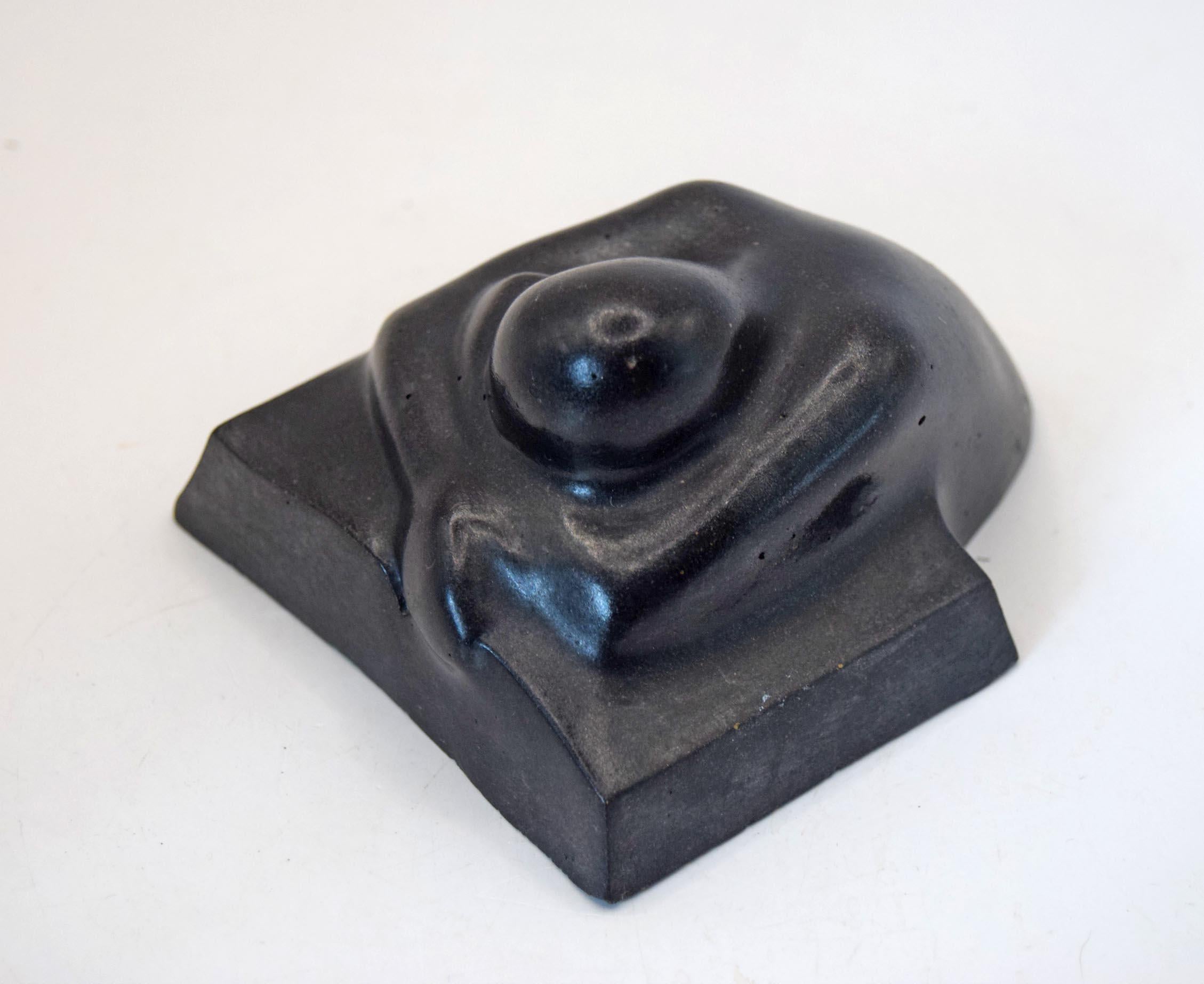 A black molded weeping man with a  flat rectangular base, photographed on a plain white background.
