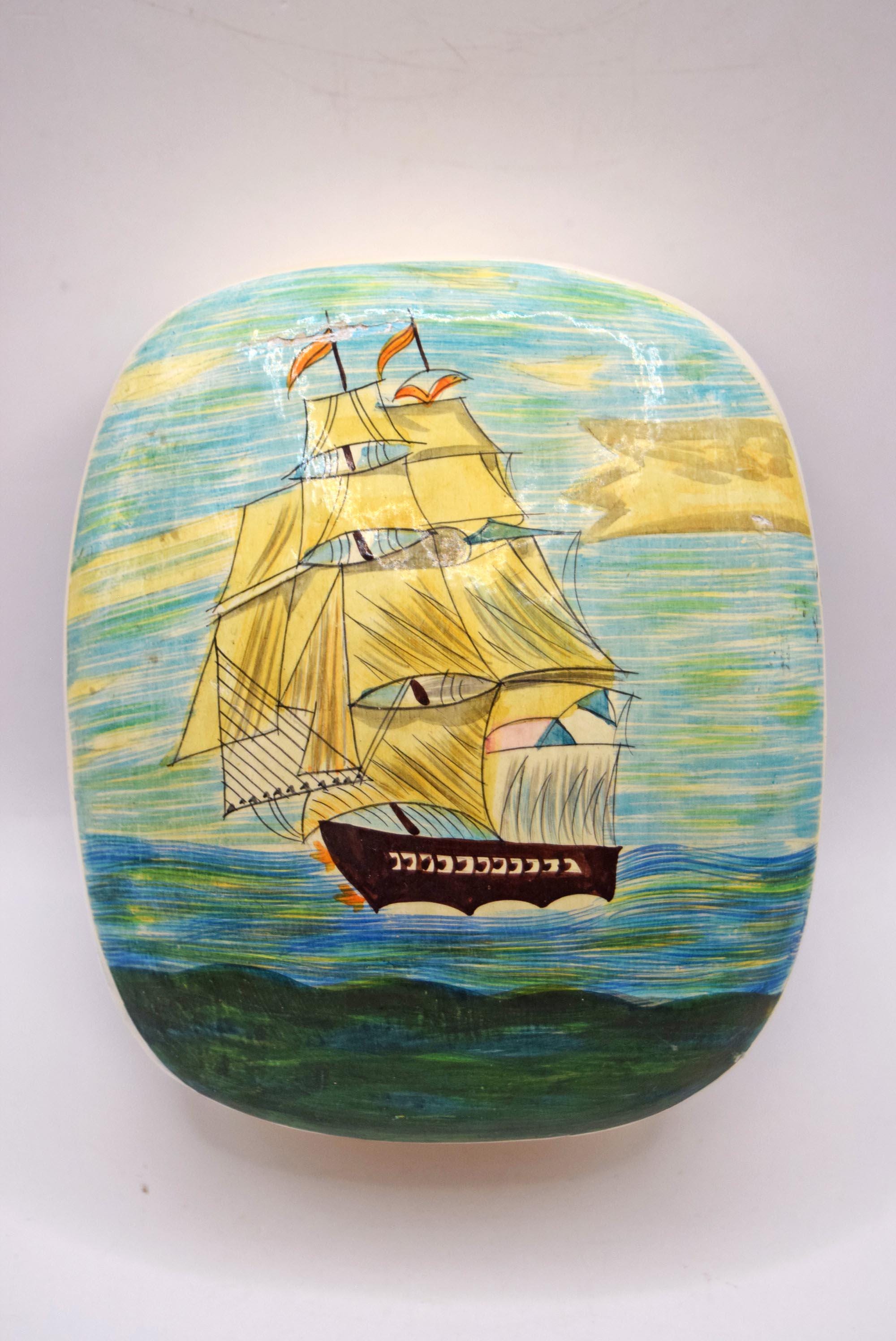 A hand-painted wooden box featuring a detailed illustration of a sailing ship on a textured blue and yellow sea background, with Hebrew text on the side.