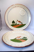 Two vintage ceramic plates with a hand-painted country landscape design featuring a small house, green hills, and blue dotted borders. The top plate has a small integrated cup, and both plates feature the printed text 'Waste not want not' on the rim.