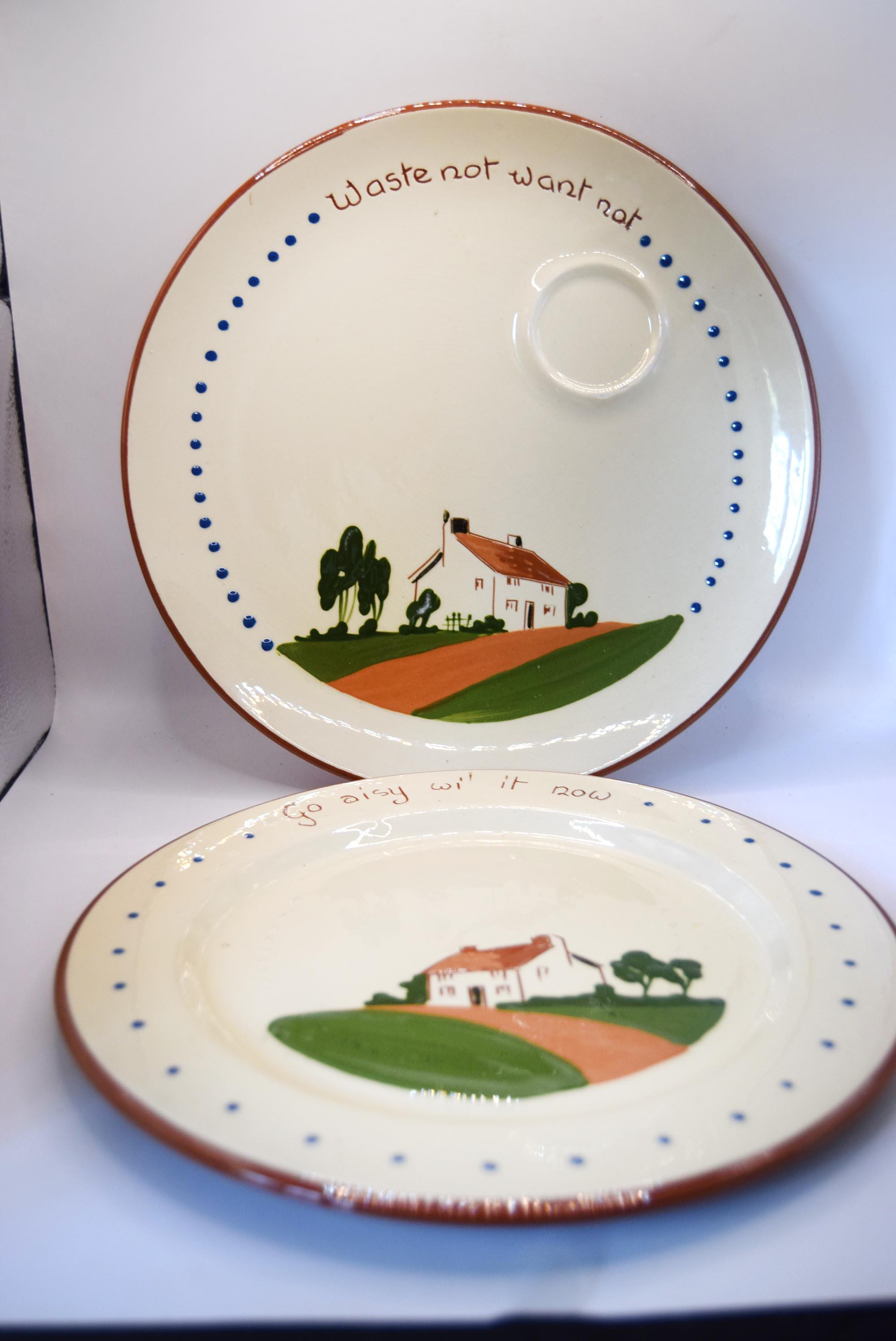 Two vintage ceramic plates with a hand-painted country landscape design featuring a small house, green hills, and blue dotted borders. The top plate has a small integrated cup, and both plates feature the printed text 'Waste not want not' on the rim.