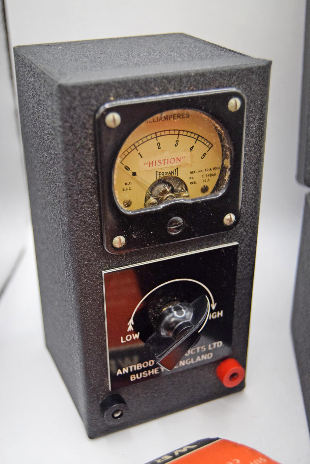 Vintage medical equipment device with a black textured housing, a round analog pressure gauge, and a rotary control knob, photographed on a white surface.
